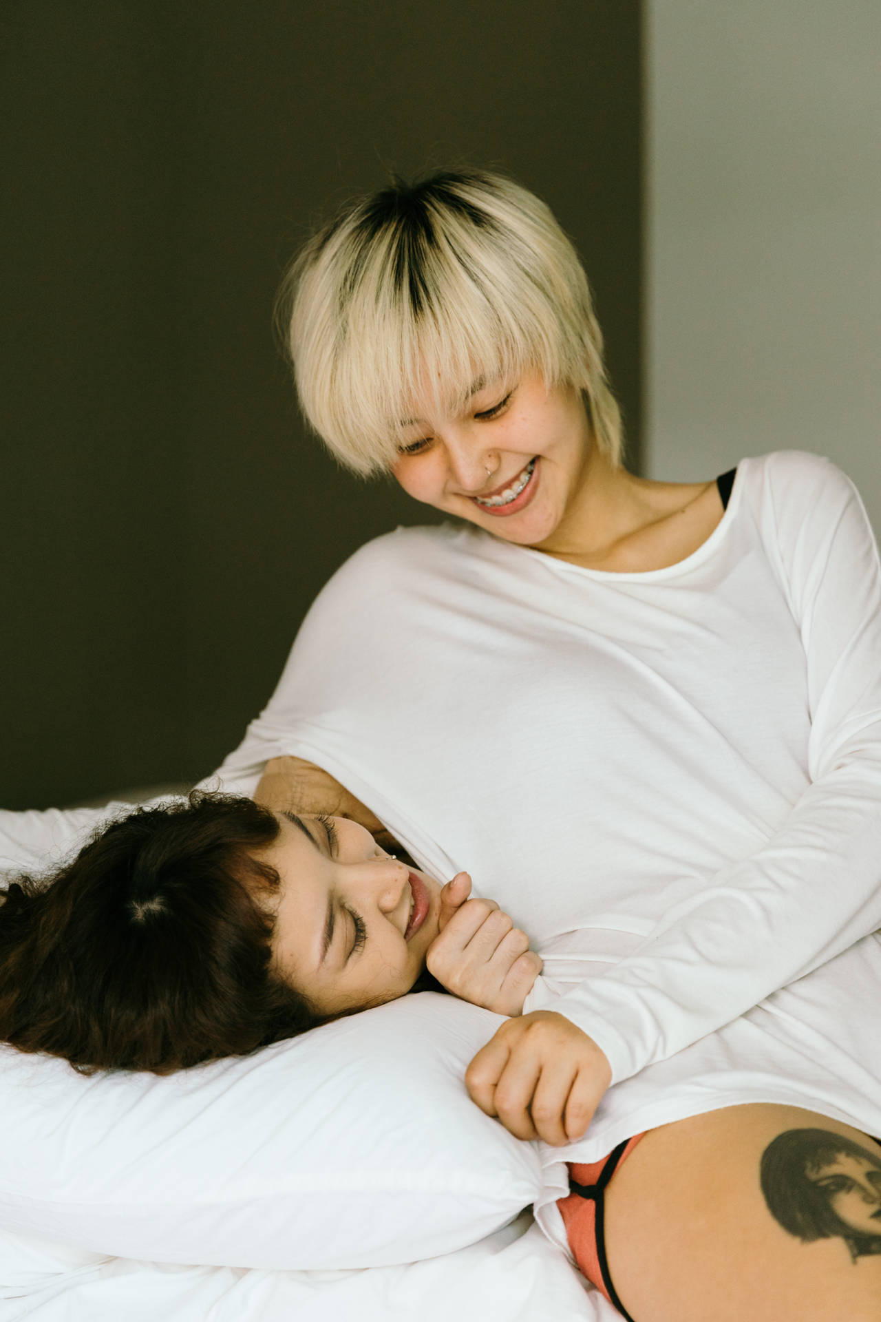 兩位女士在白色床單的床上一起歡笑和休息。