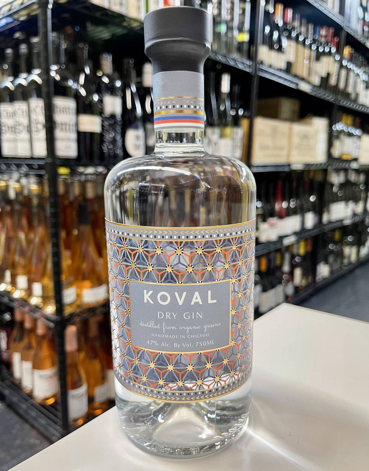 一瓶Koval Dry Gin放在商店櫃檯上，後面有酒架。
