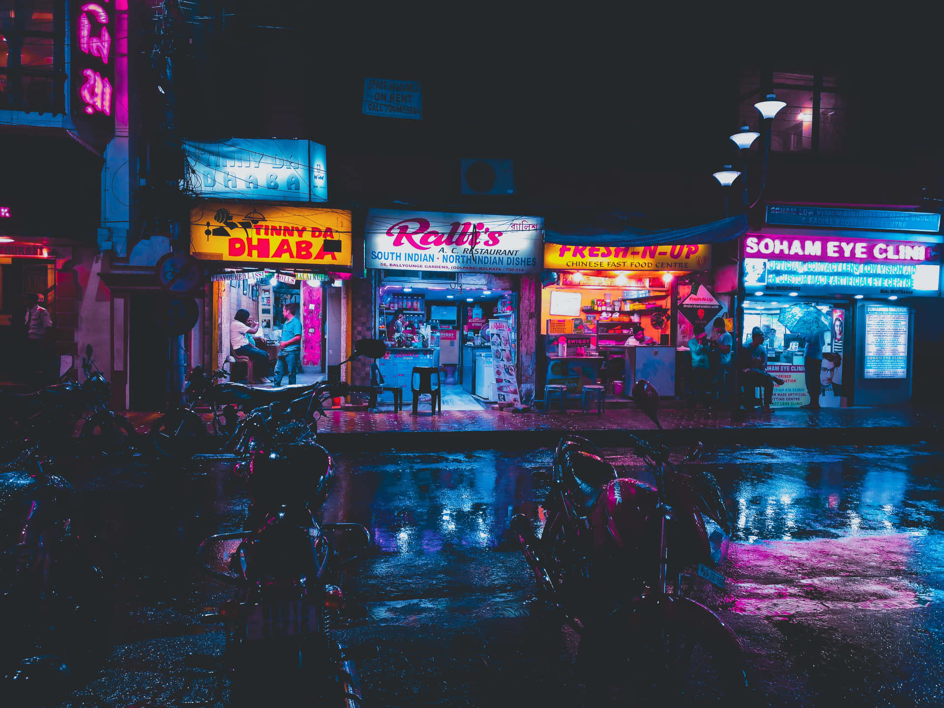 夜晚街景，發光的霓虹招牌在潮濕的人行道上反射。