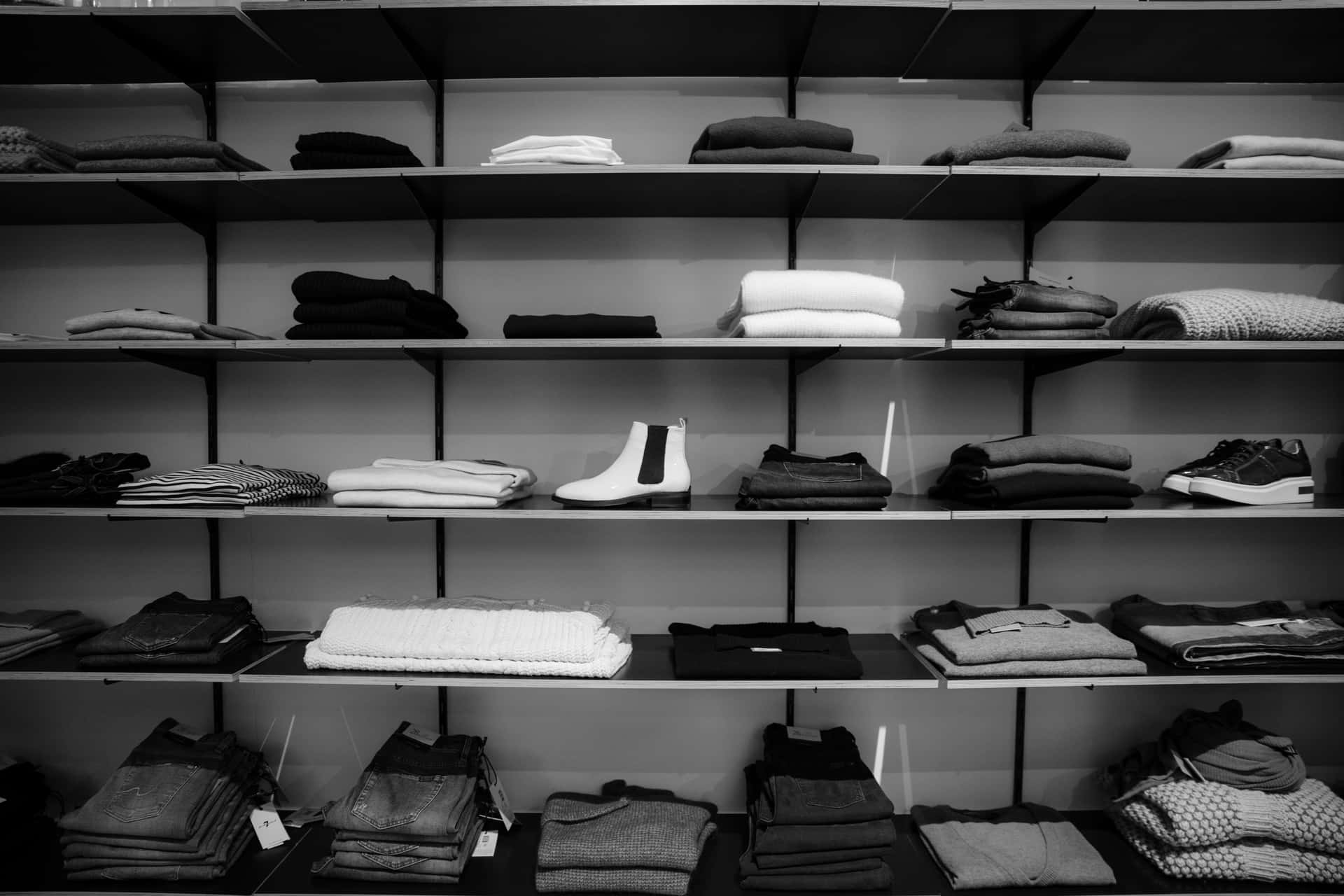 現代商店中極簡主義貨架上整齊折疊的衣服和鞋子。