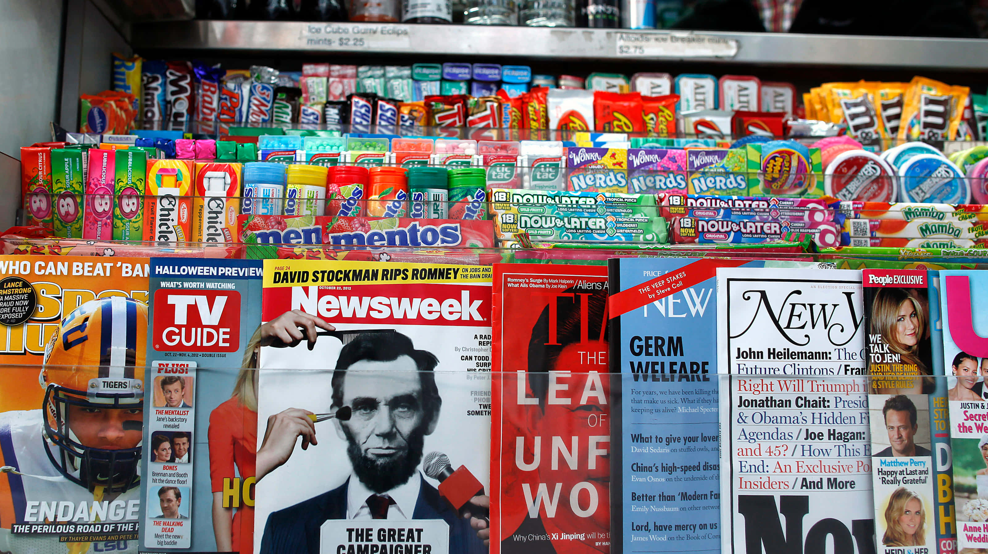 Magazine 桌布 壁紙 — 店舖貨架上色彩繽紛的糖果棒和雜誌，搭配大膽標題和明亮包裝，充滿活力。