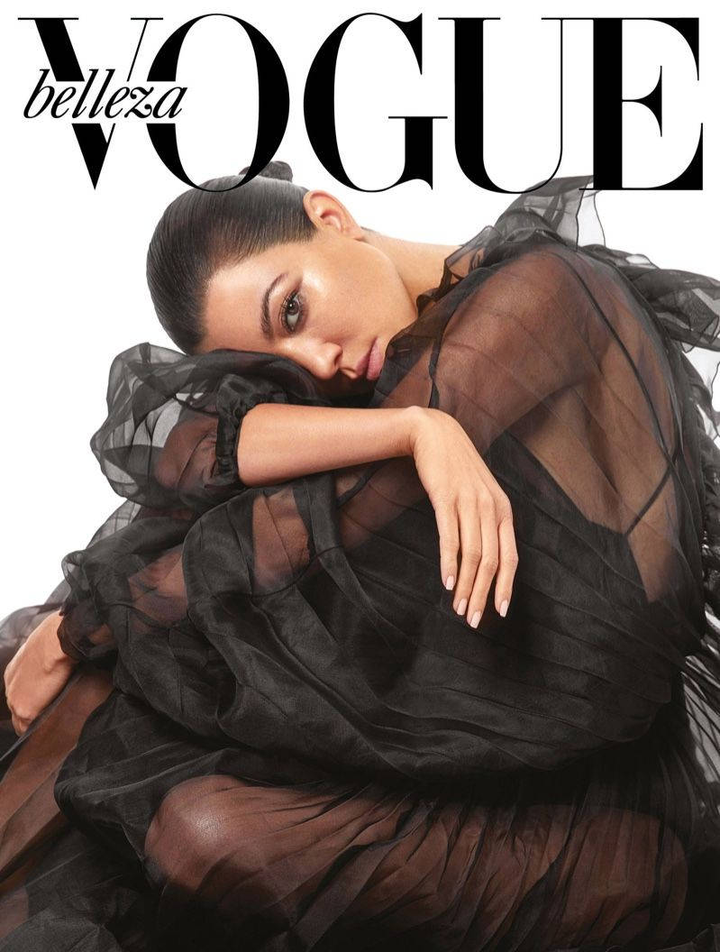 身穿黑色透視裙的模特兒為Vogue雜誌封面擺姿勢。