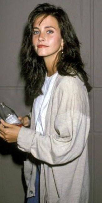 1990年代休閒裝扮的女性在室內手持玻璃瓶。