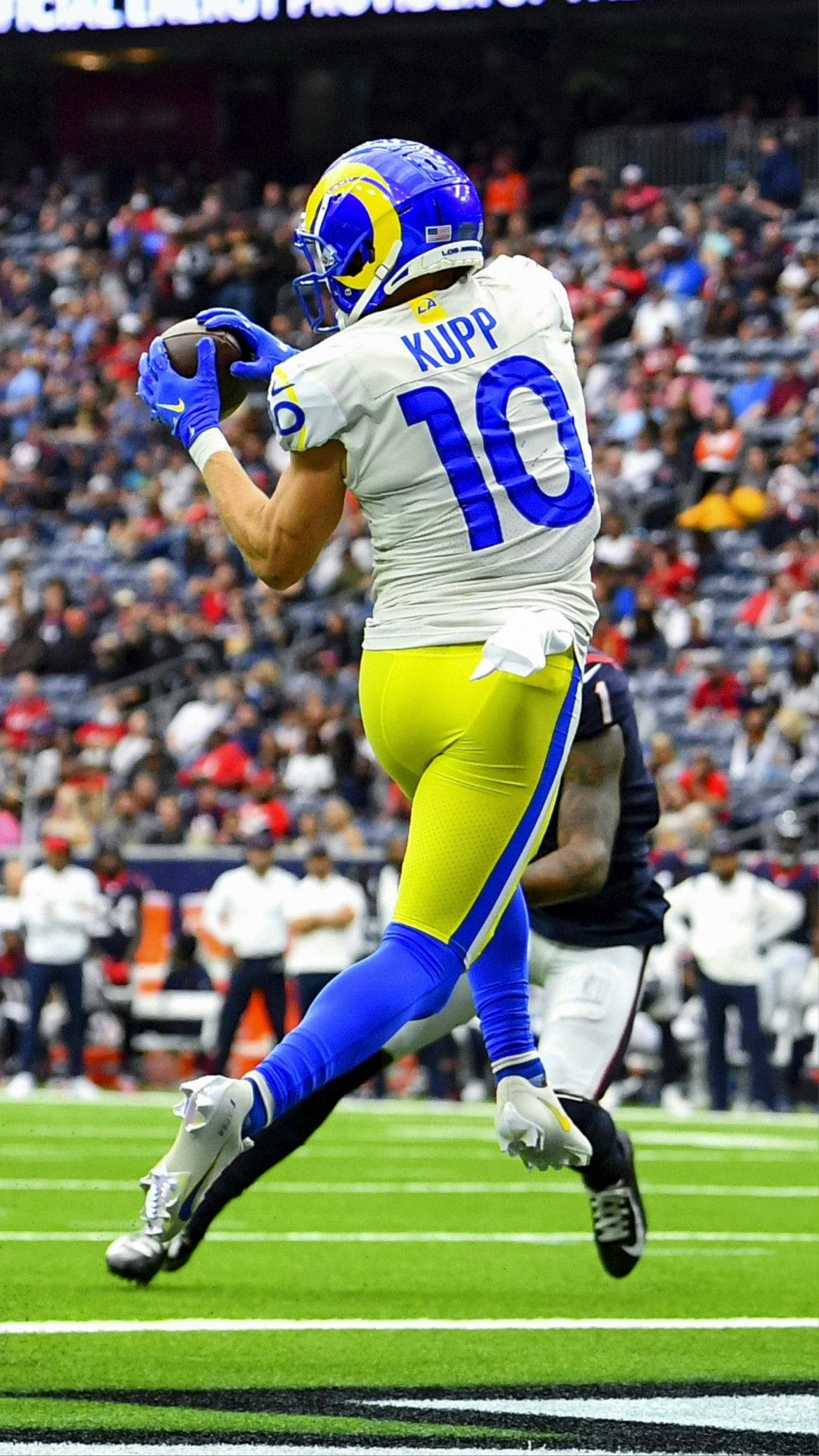 庫珀·庫普 NFL 洛杉磯公羊隊動態攝影 壁紙 — 一名身穿藍黃裝備的洛杉磯公羊美式足球員在球場燈光下跳起接球。