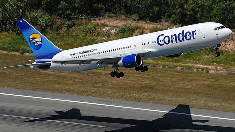 Condor Thomas Cook飛機在綠色山丘背景下降落跑道。