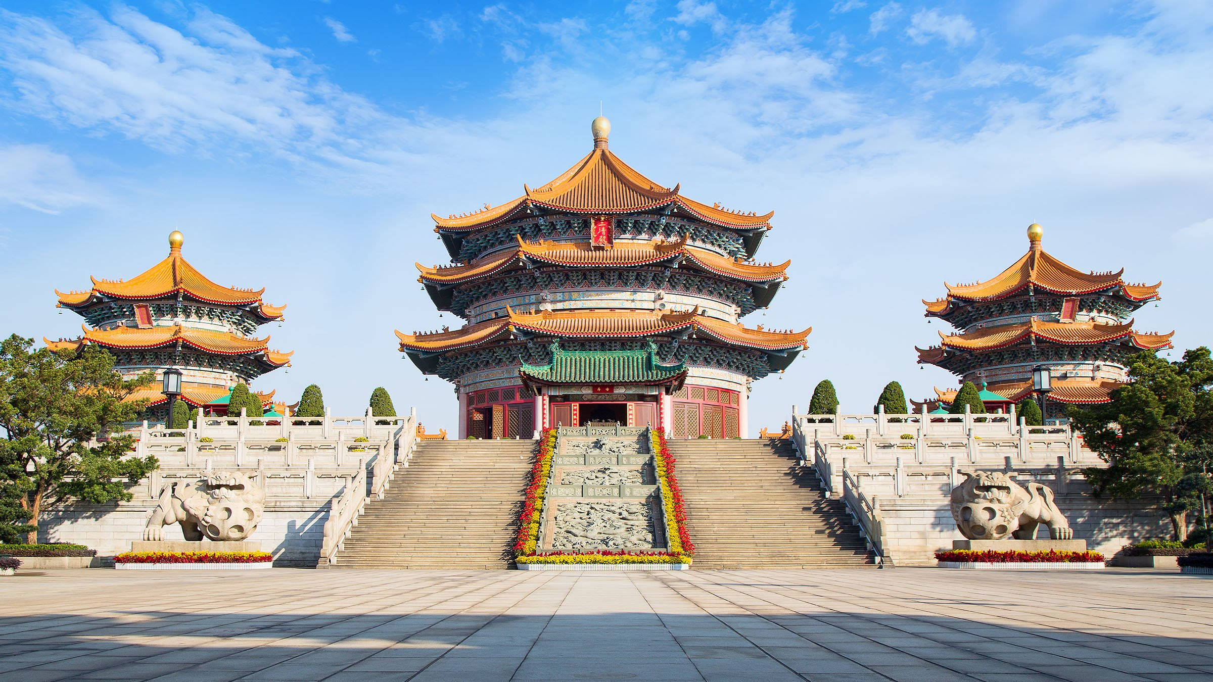 廣州元玄道觀 壁紙 — 宏偉的傳統中國寺廟建築群，擁有層疊的橙色屋頂和石獅雕像，在明亮的藍天下。