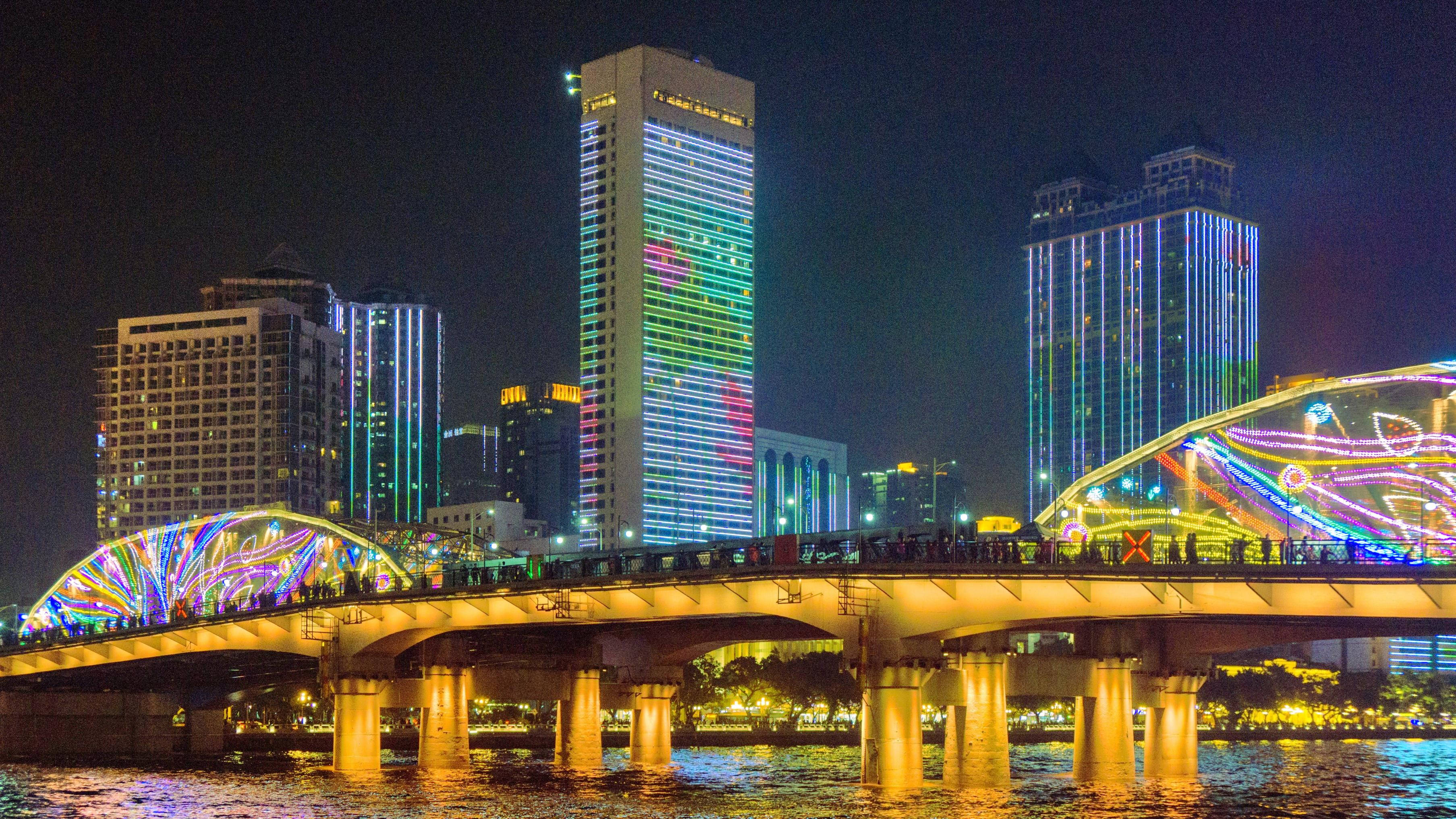 廣州海珠橋 壁紙 — 充滿活力的夜景，以一座燈火通明的拱橋橫跨水面，背景是色彩繽紛的摩天大樓。