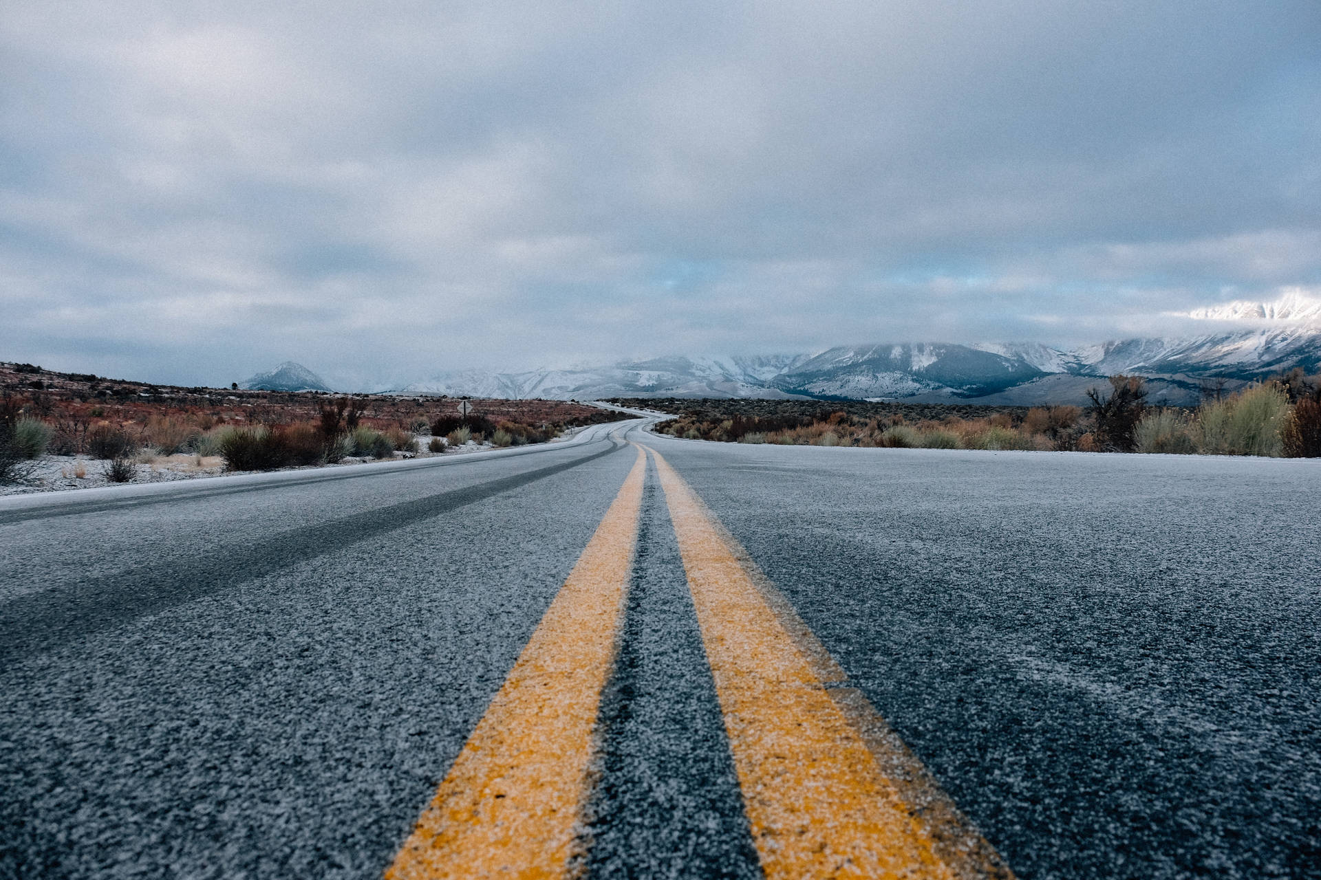 蜿蜒的道路在陰沉天空下通往積雪覆蓋的山脈。