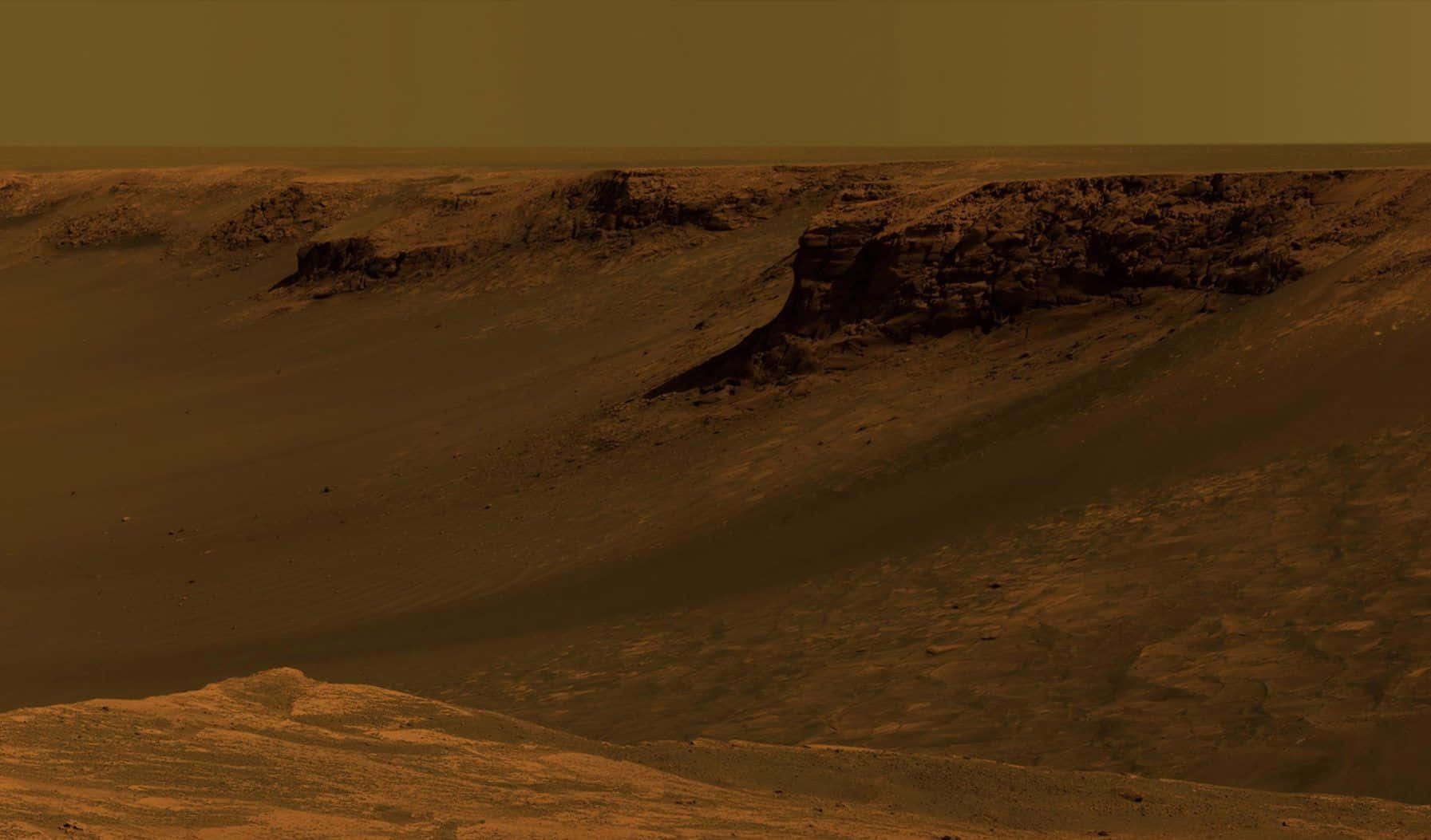 Mars Landscape 桌布 壁紙 — 廣闊嘅鏽紅色火星景觀，有起伏嘅沙丘同層狀岩石結構，喺朦朧嘅橙色天空下。