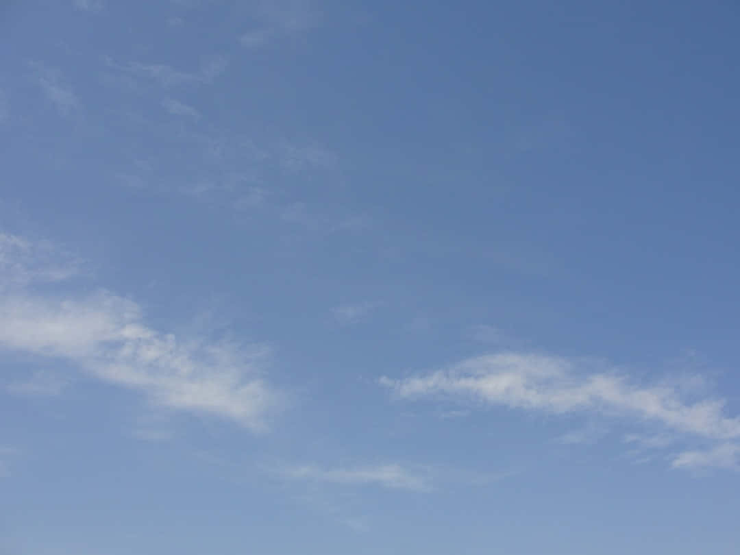 Blue Skies 桌布 壁紙 — 廣闊寧靜的藍天，縷縷白雲輕輕飄過地平線。
