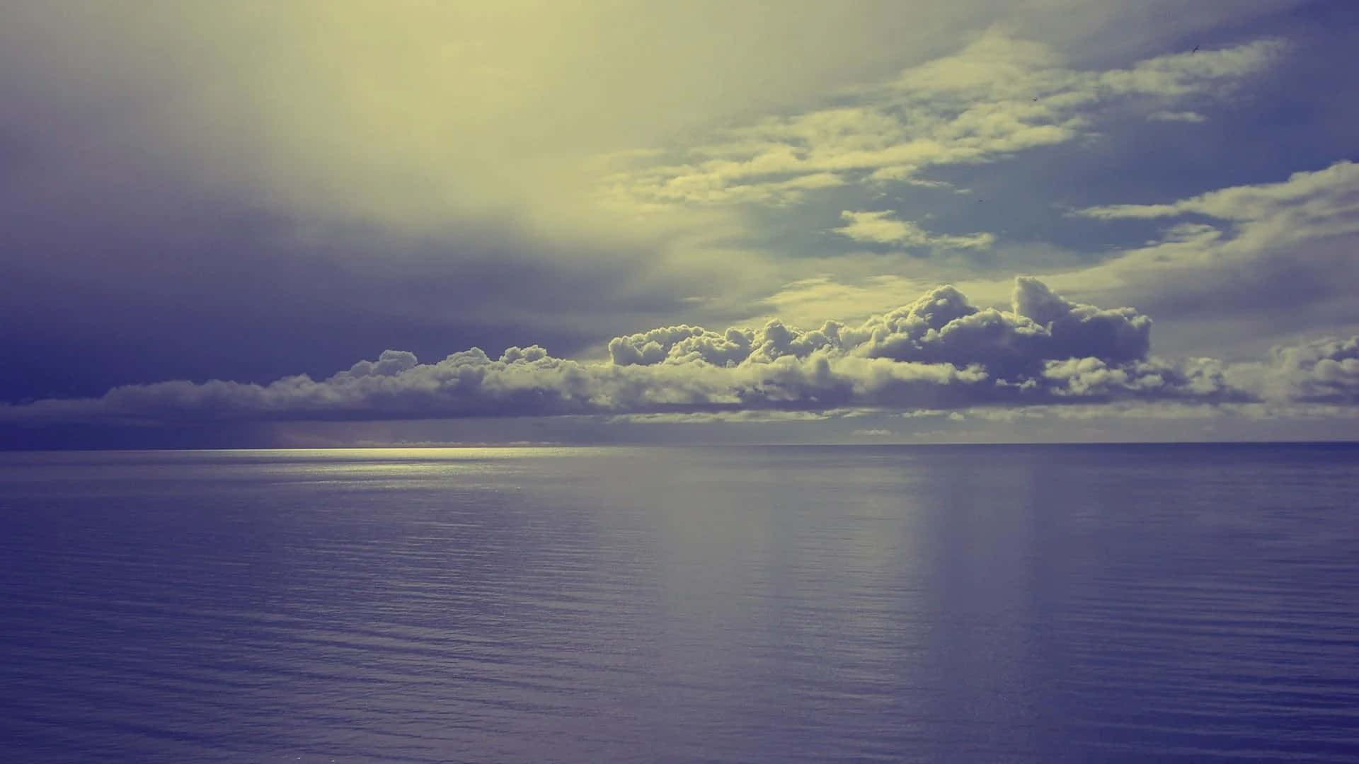 Horizon 桌布 壁紙 — 廣闊海洋遇上戲劇性天空，陽光穿透雲層，營造出寧靜的黃昏場景。