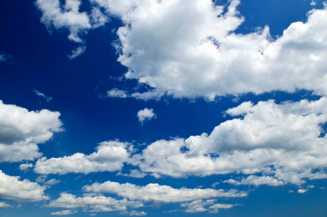Blue Skies 桌布 壁紙 — 廣闊深藍天空，充滿蓬鬆白雲在晴朗夏日飄移。