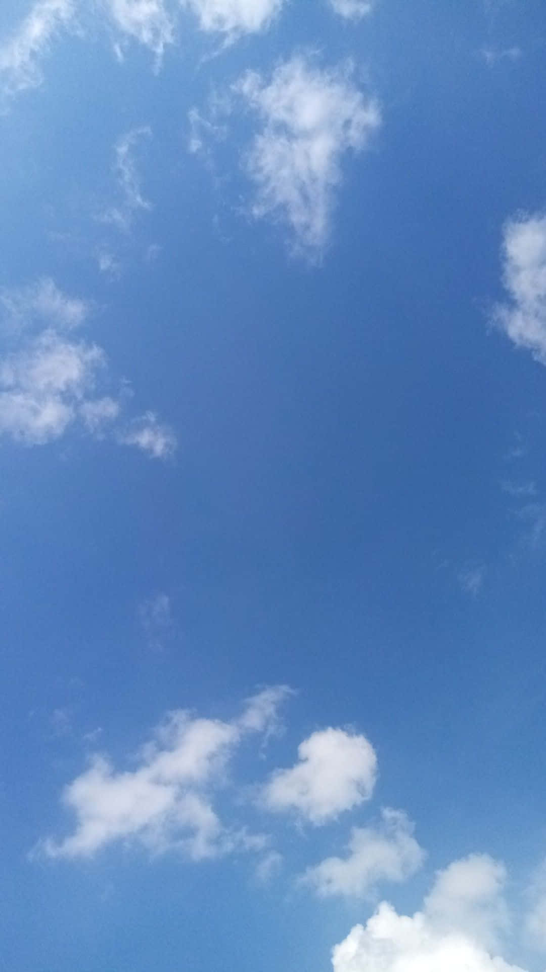 Blue Horizon 桌布 壁紙 — 廣闊清澈的藍天，在明亮的日光下點綴著縷縷白雲。