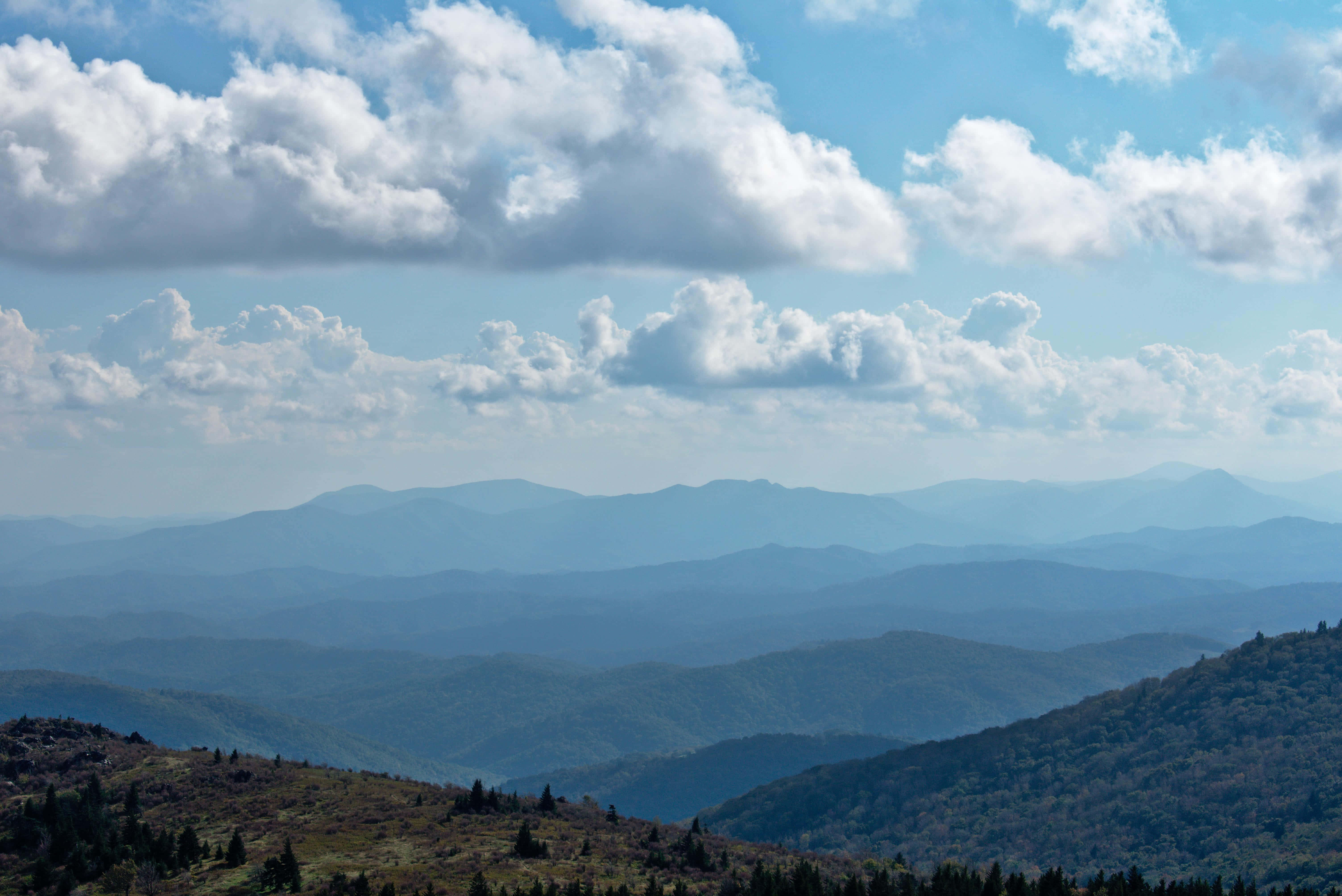 Blue Ridge Mountains 桌布 壁紙 — 廣闊的山脈在明亮的藍天白雲下延伸至遠方。