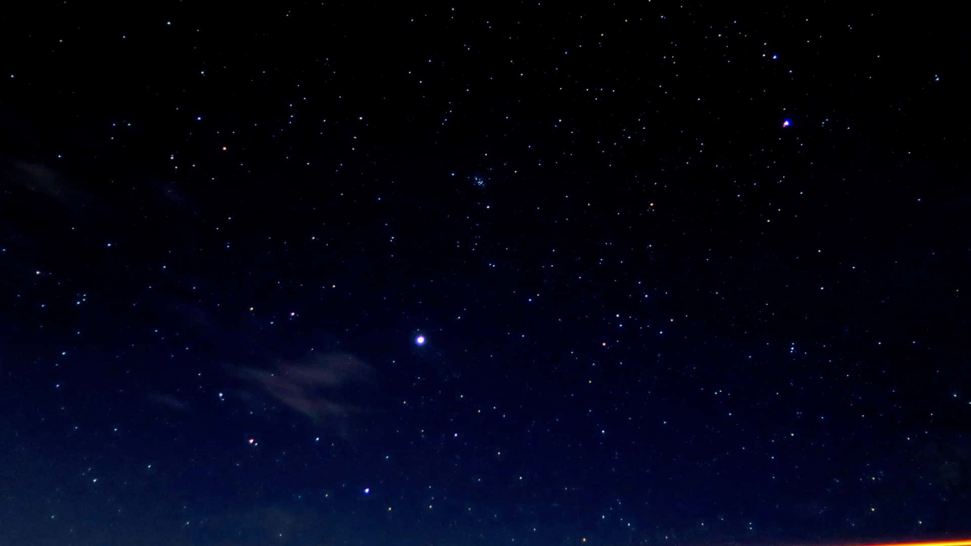 星空 桌布 壁紙 — 廣闊的星空夜空，閃爍的星星和淡淡的雲朵，散發著微妙的橙色地平線。