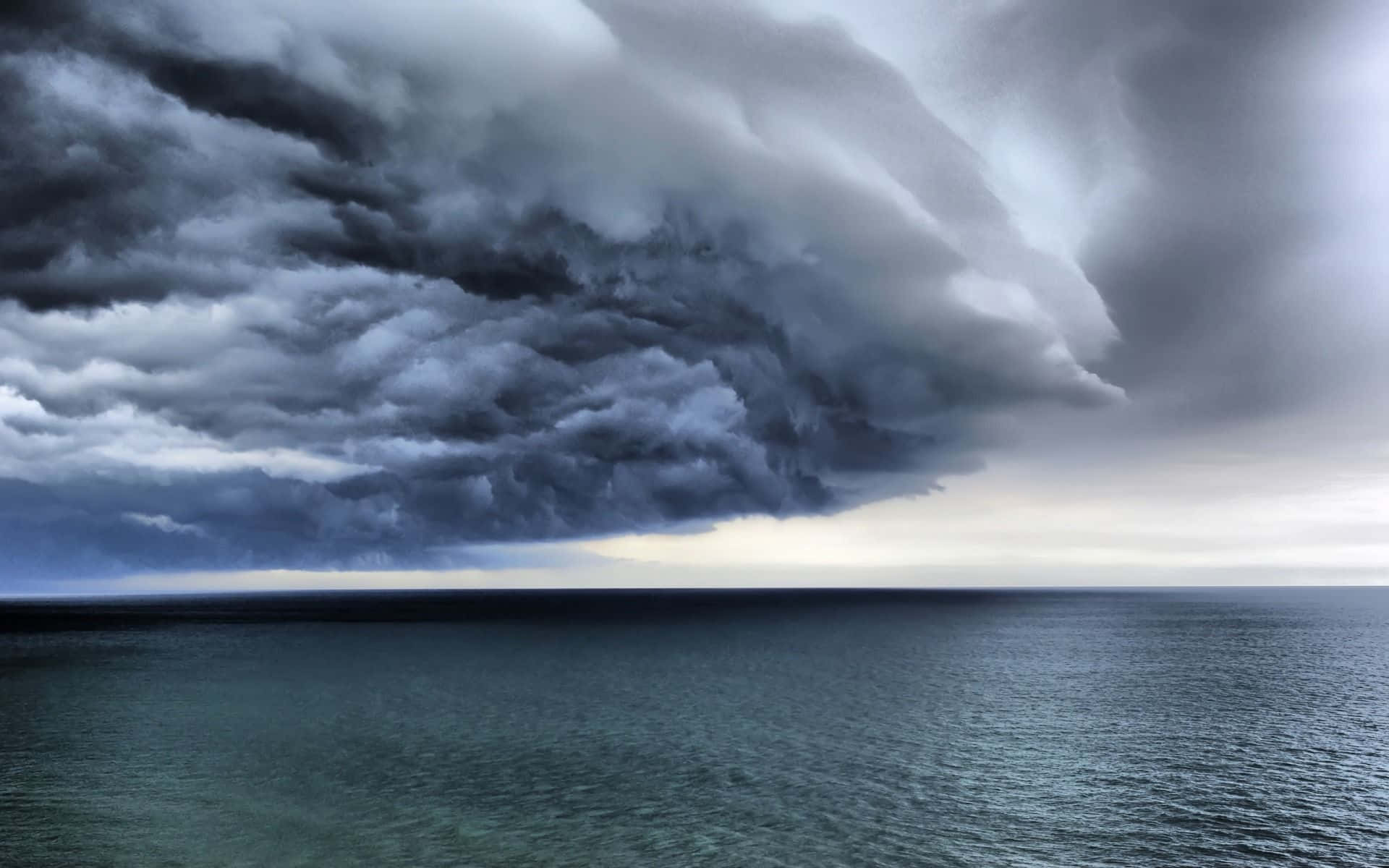 Thunderstorm 桌布 壁紙 — 廣闊的海洋延伸在從地平線滾滾而來的黑暗風暴雲高聳的牆壁之下。