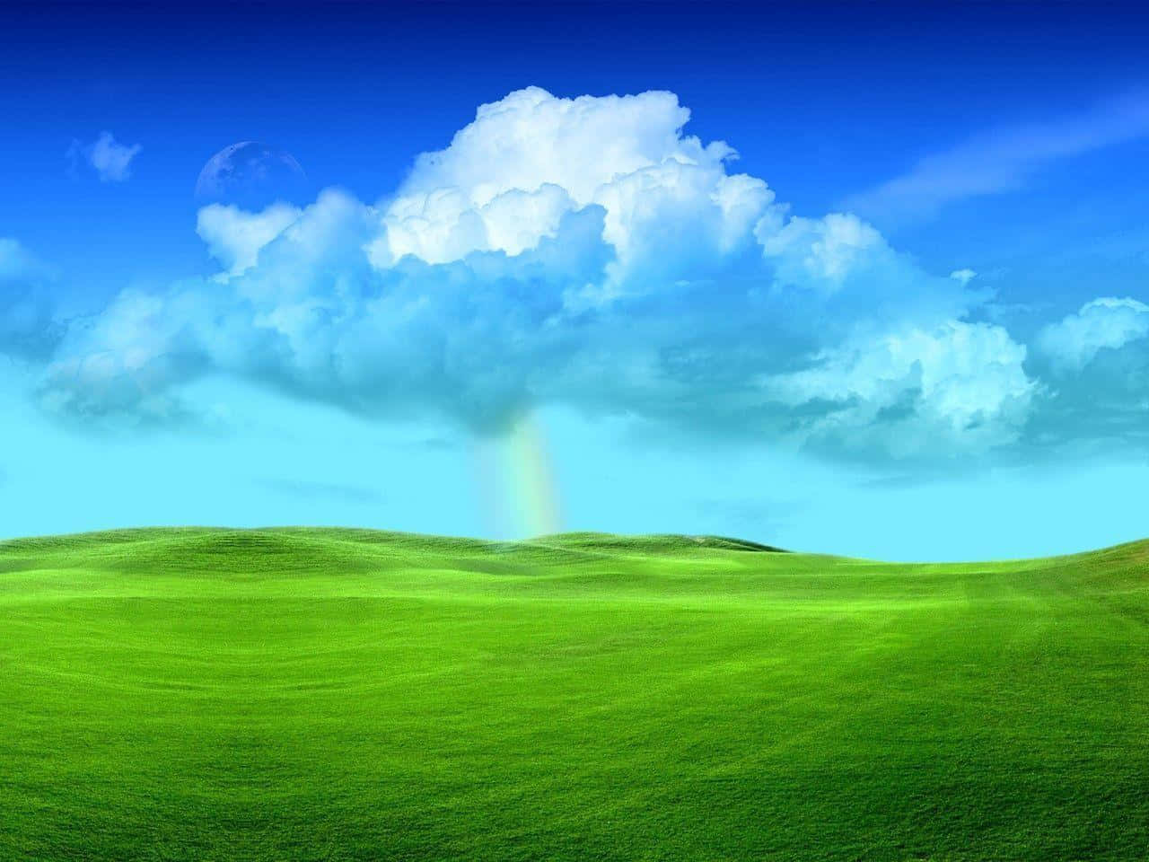 Windows Vista 桌布 壁紙 — 廣闊的綠色起伏山丘在明亮的藍天下延伸，一朵大而蓬鬆的雲朵將微弱的彩虹雨灑在草地上。