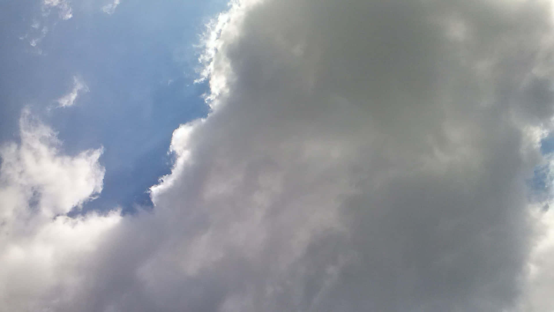 SKY-26 壁紙 — 廣闊藍天被大量白色和灰色雲層穿透，投下柔和陰影。