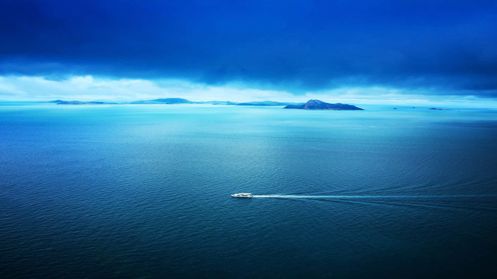 一艘快艇在暴風雨天空下，與遙遠的島嶼一起航行在廣闊的藍色海洋上。