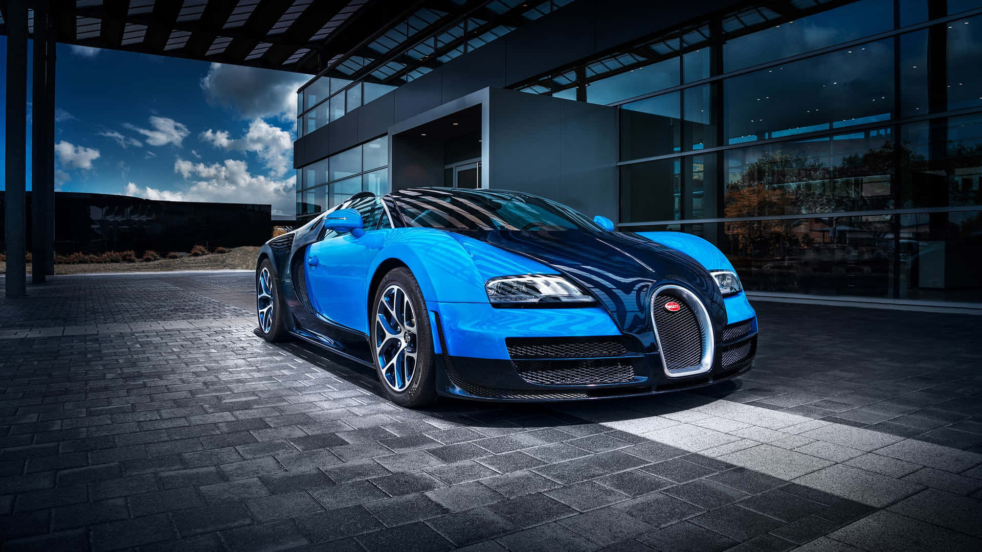 日落時分，一輛藍色Bugatti跑車停在一棟現代玻璃建築前。