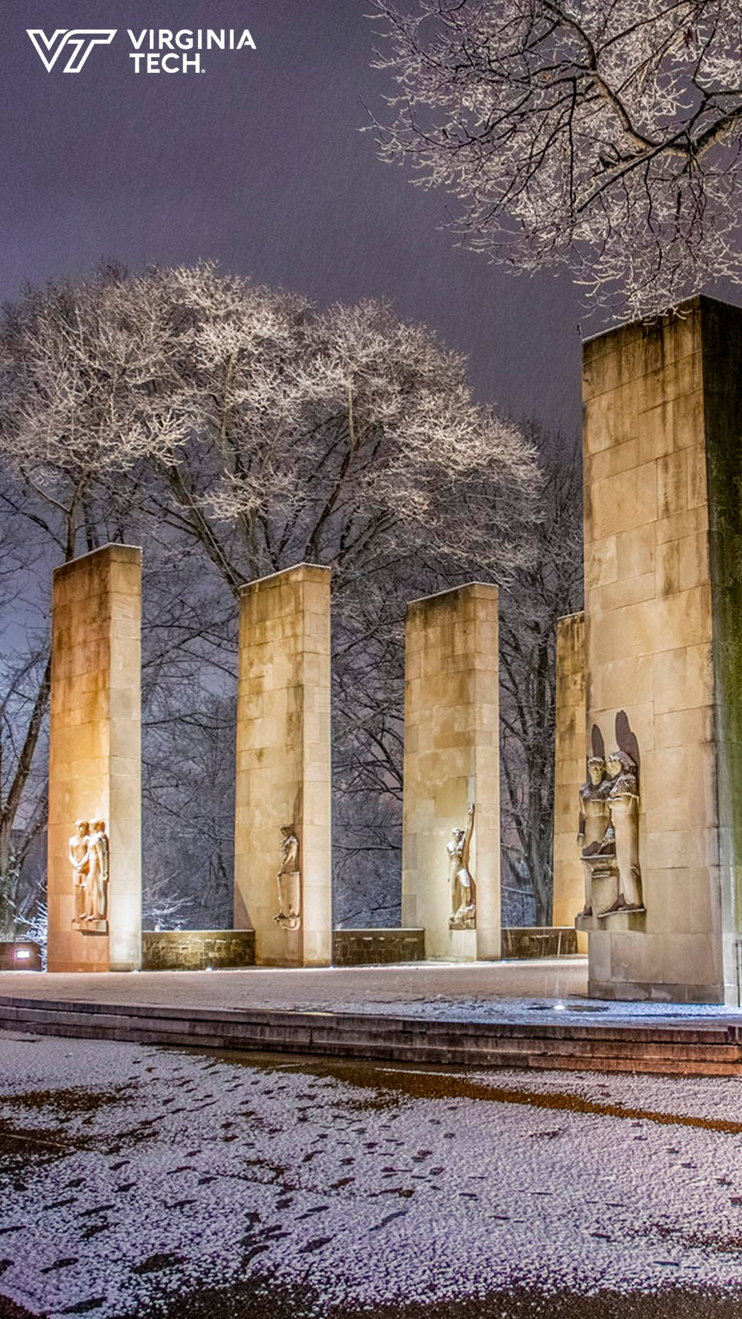 夜間大學紀念碑周圍被照亮的石柱附近的雪覆蓋地面。