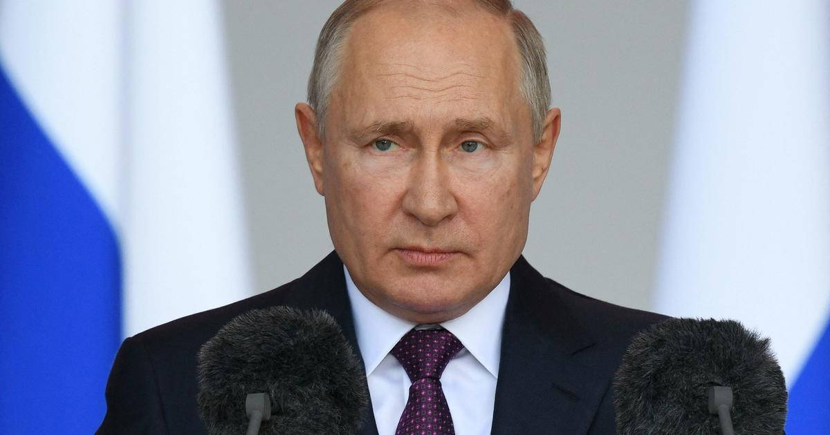 弗拉基米尔·普京在講台前神情嚴肅 壁紙 — 弗拉基米爾·普京身穿深色西裝和圖案領帶的特寫，站在麥克風前，背景有模糊的俄羅斯國旗。