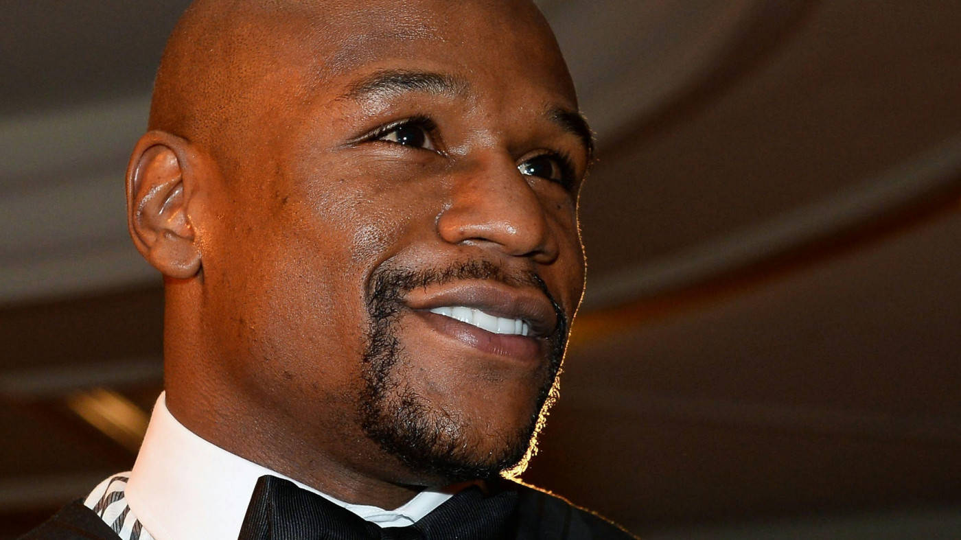 弗洛伊德·梅威瑟穿著正裝微笑 壁紙 — 弗洛伊德·梅威瑟（Floyd Mayweather Jr.）在柔和室內燈光下穿著燕尾服，溫暖微笑的特寫肖像。