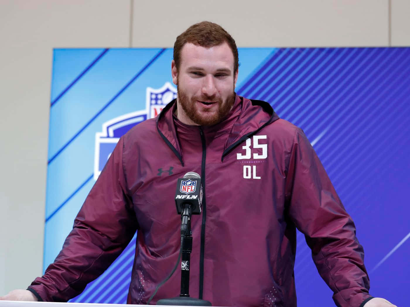 NFL進攻鋒線球員穿著棗紅色外套在新聞發布會上發言。