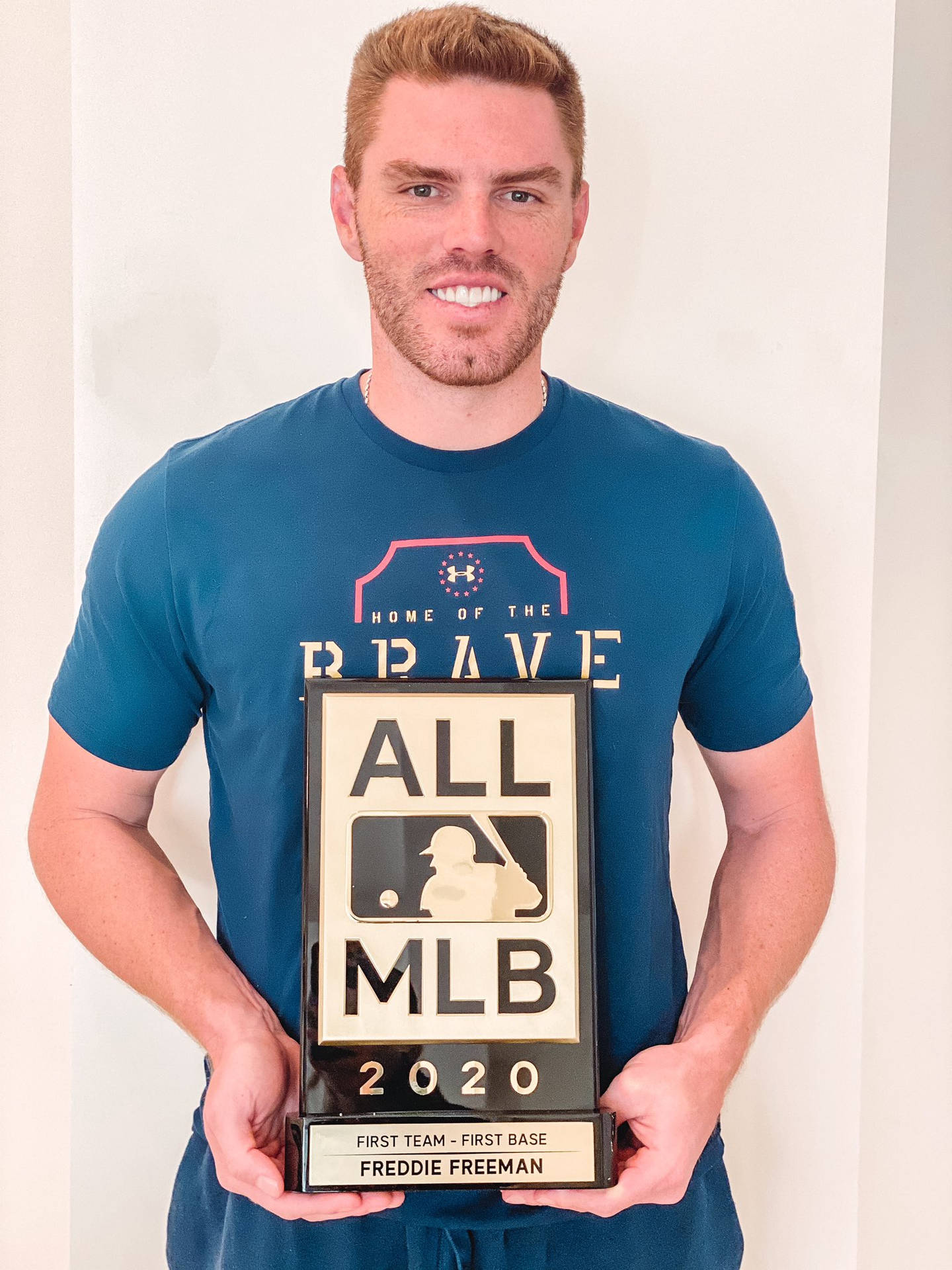 棒球運動員Freddie Freeman在室內舉起他的2020年全MLB第一隊獎盃。