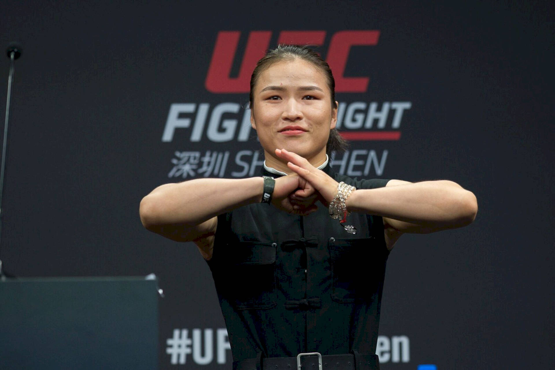 UFC拳手在記者會上雙臂交叉身穿黑色服裝。