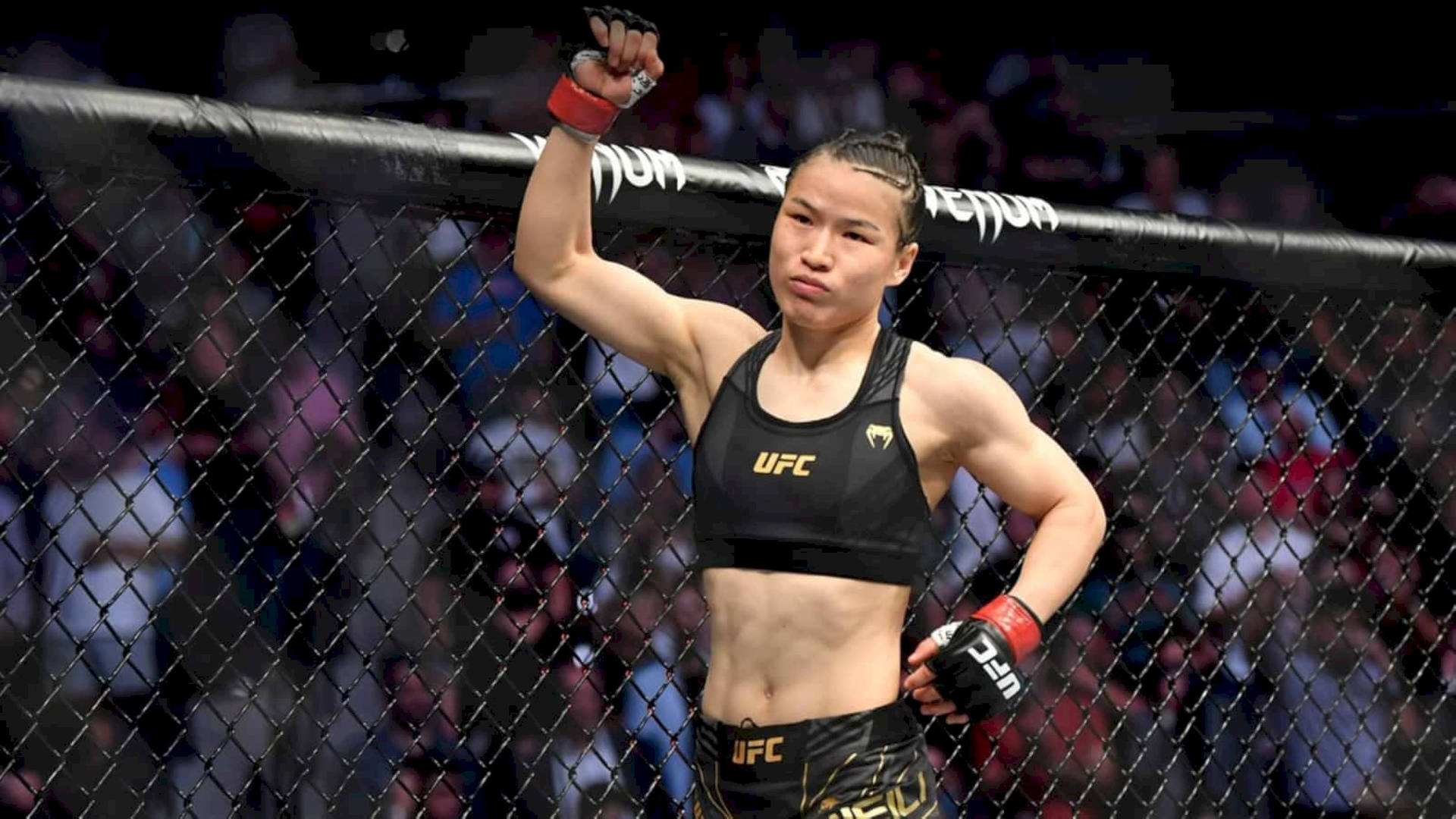 女性MMA拳手在UFC八角籠中高舉拳頭慶祝勝利。