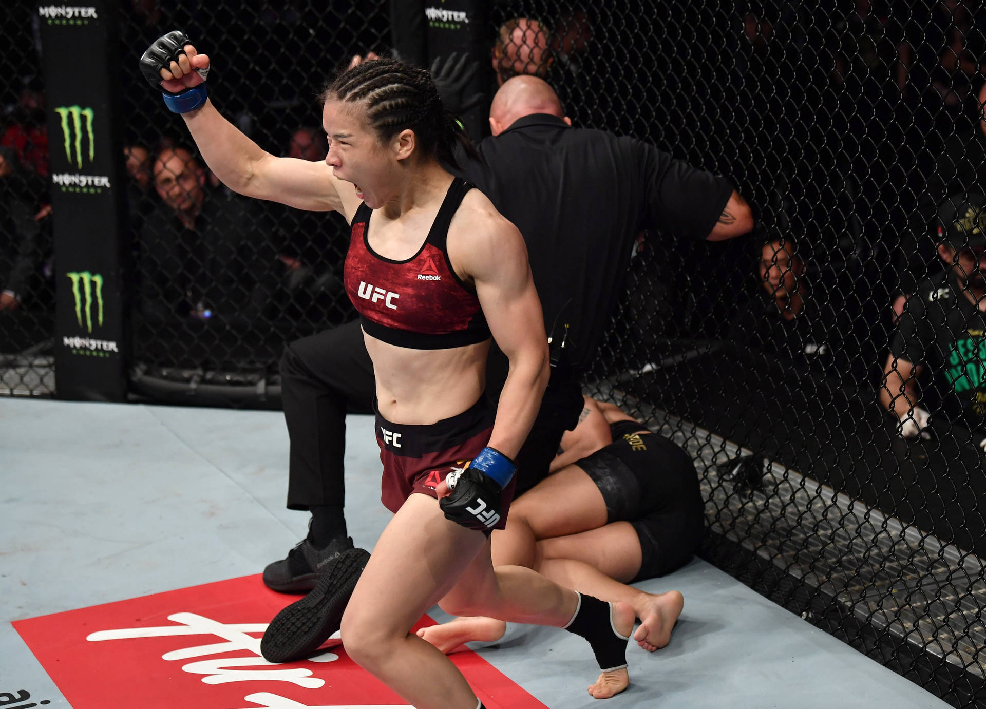 女性MMA拳手在UFC八角籠中慶祝勝利，裁判停止比賽。