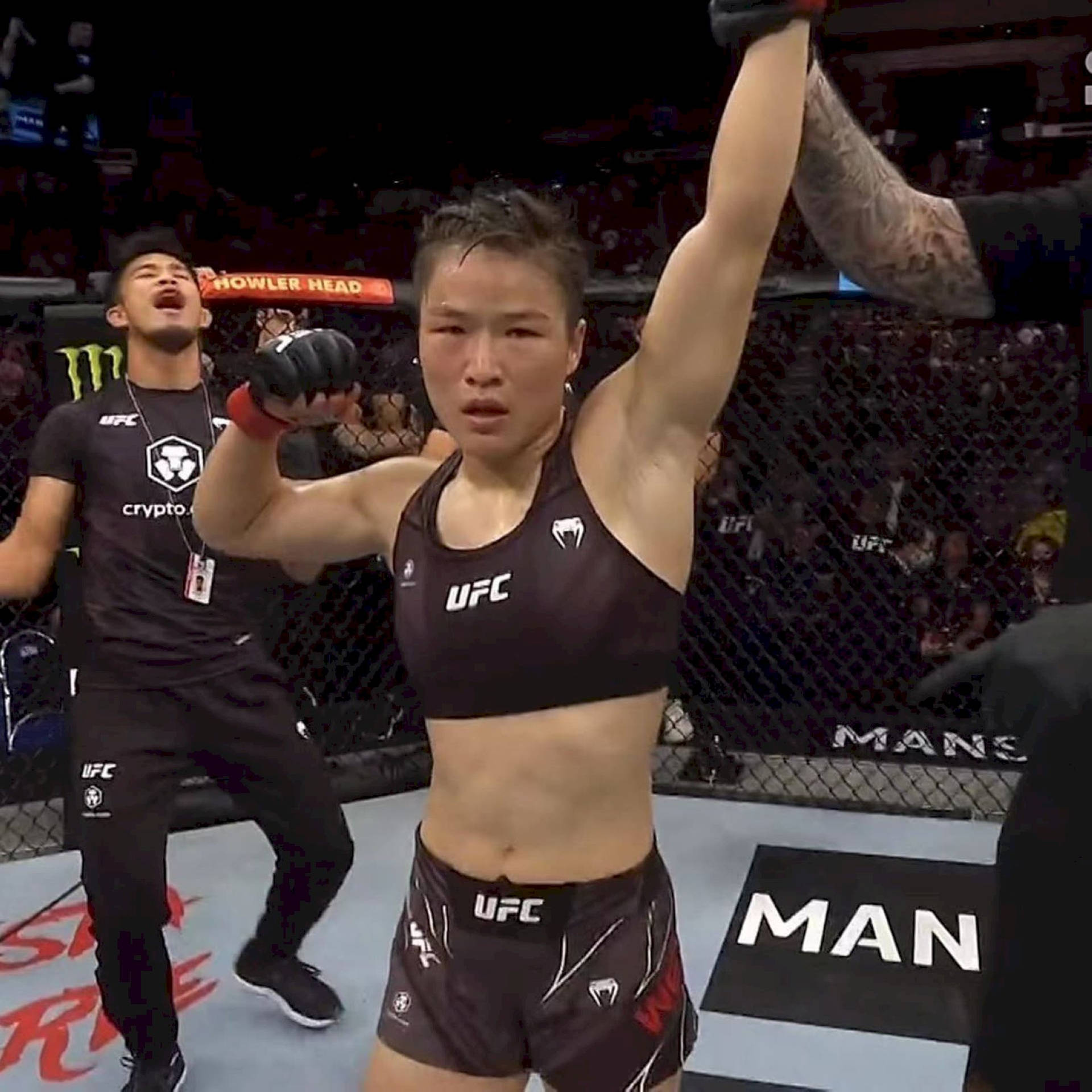 女性MMA拳手在UFC八角籠中與教練慶祝勝利。