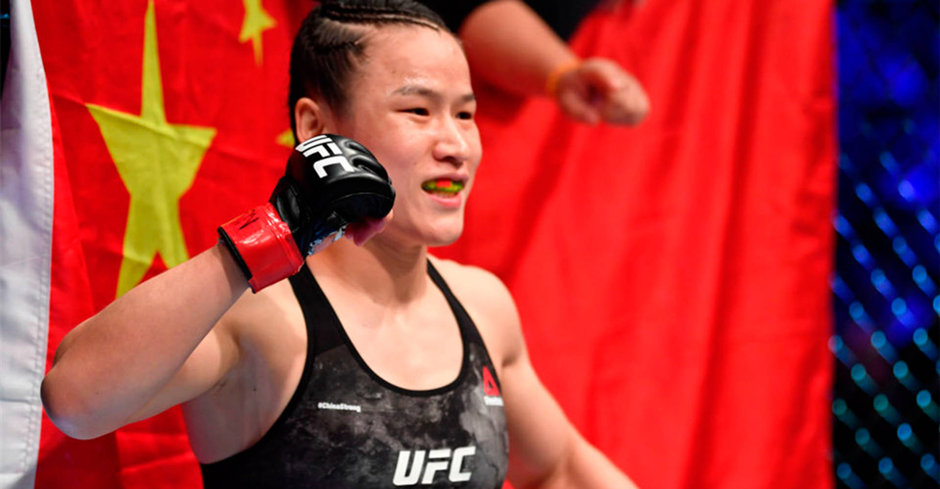 女性MMA拳手身穿UFC裝備舉拳慶祝勝利。