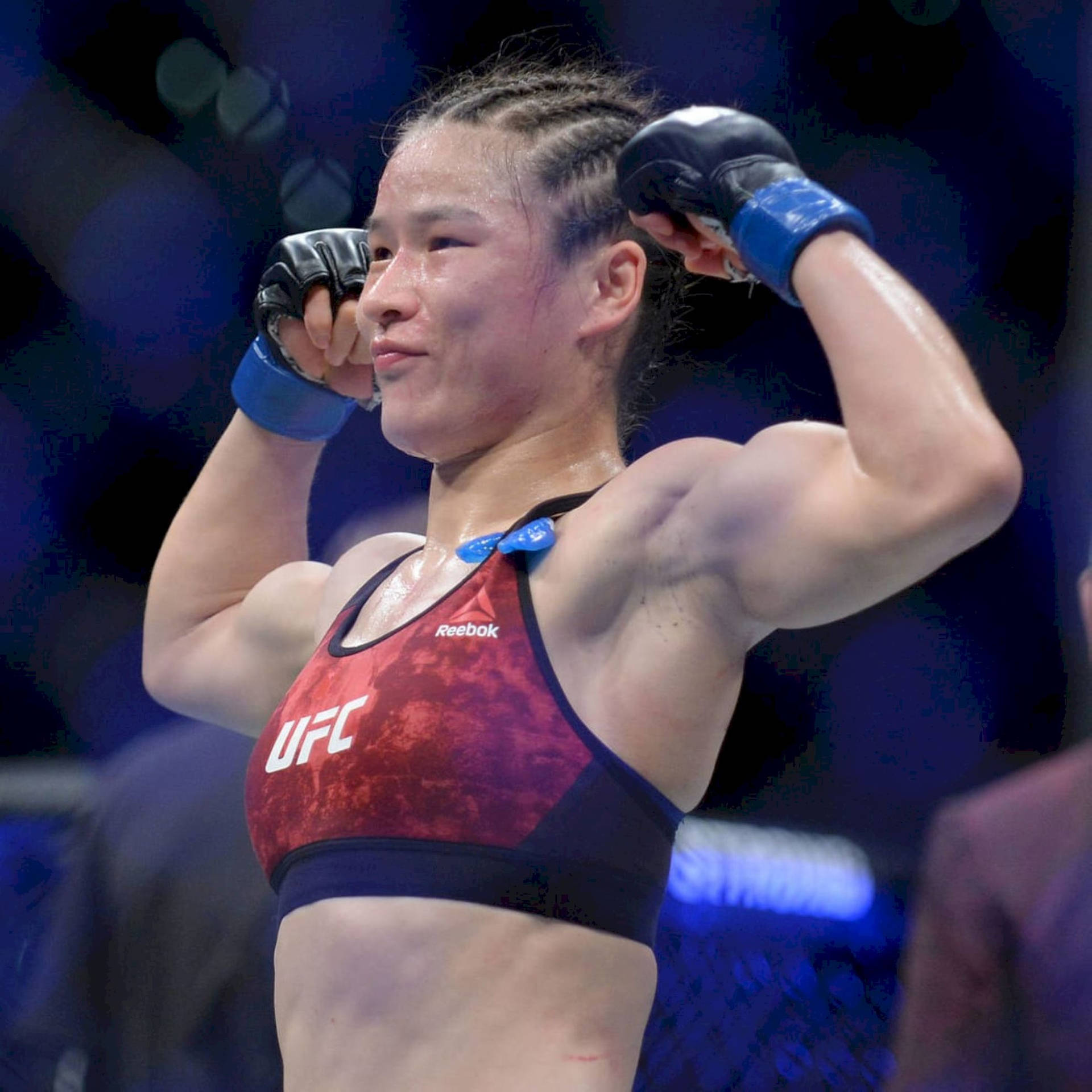 女MMA拳手在UFC八角籠內高舉拳頭慶祝勝利。