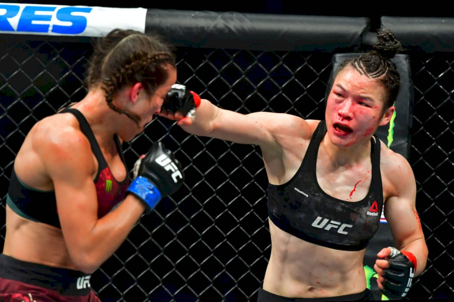 兩名女性拳手在UFC八角籠比賽中互相出拳，可見血跡。