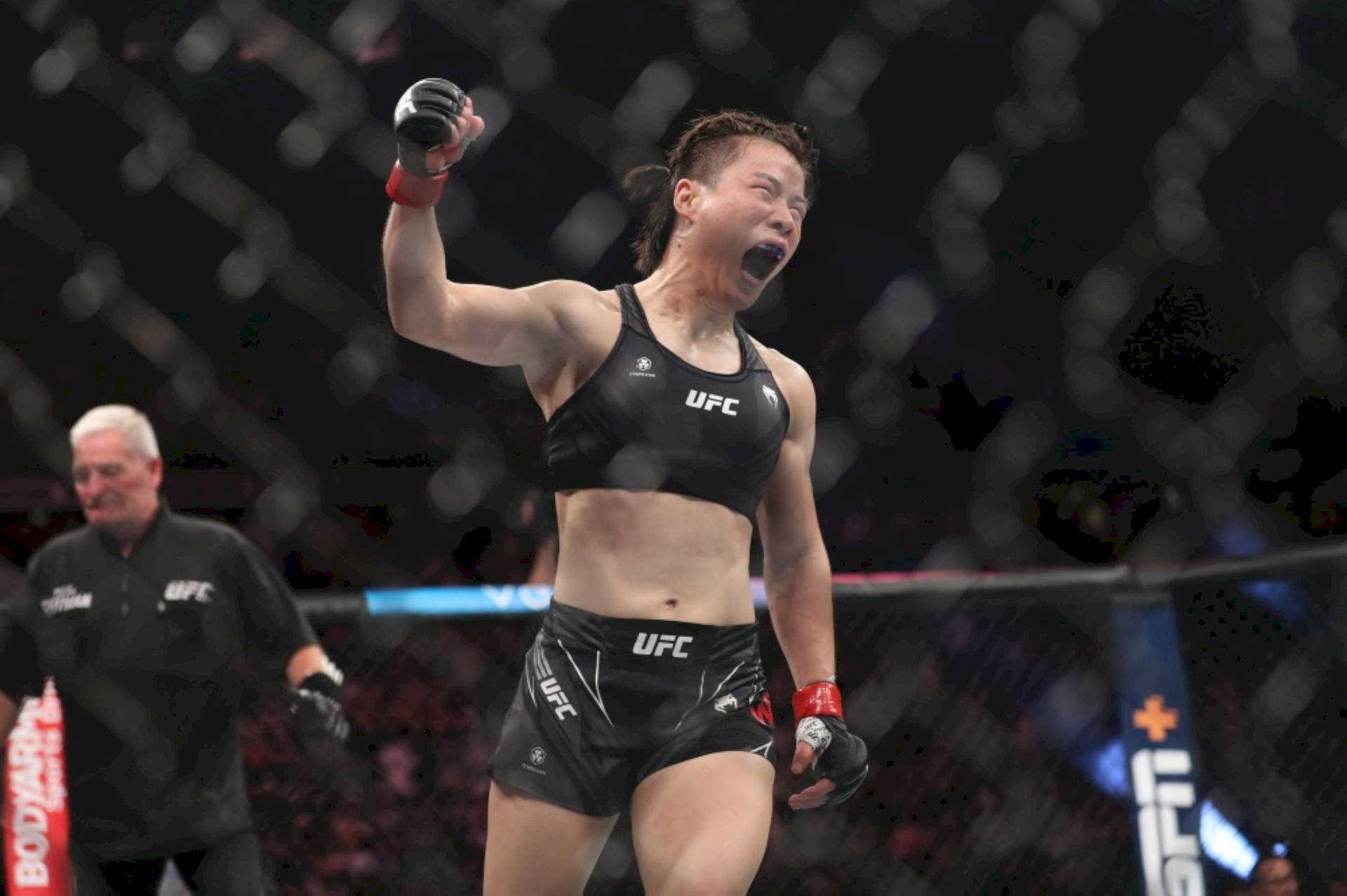 女性MMA拳手在UFC八角籠內高舉拳頭慶祝勝利。
