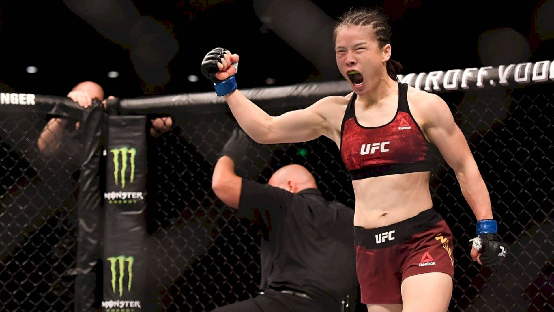 女性MMA拳手在UFC八角籠中高舉拳頭慶祝勝利。