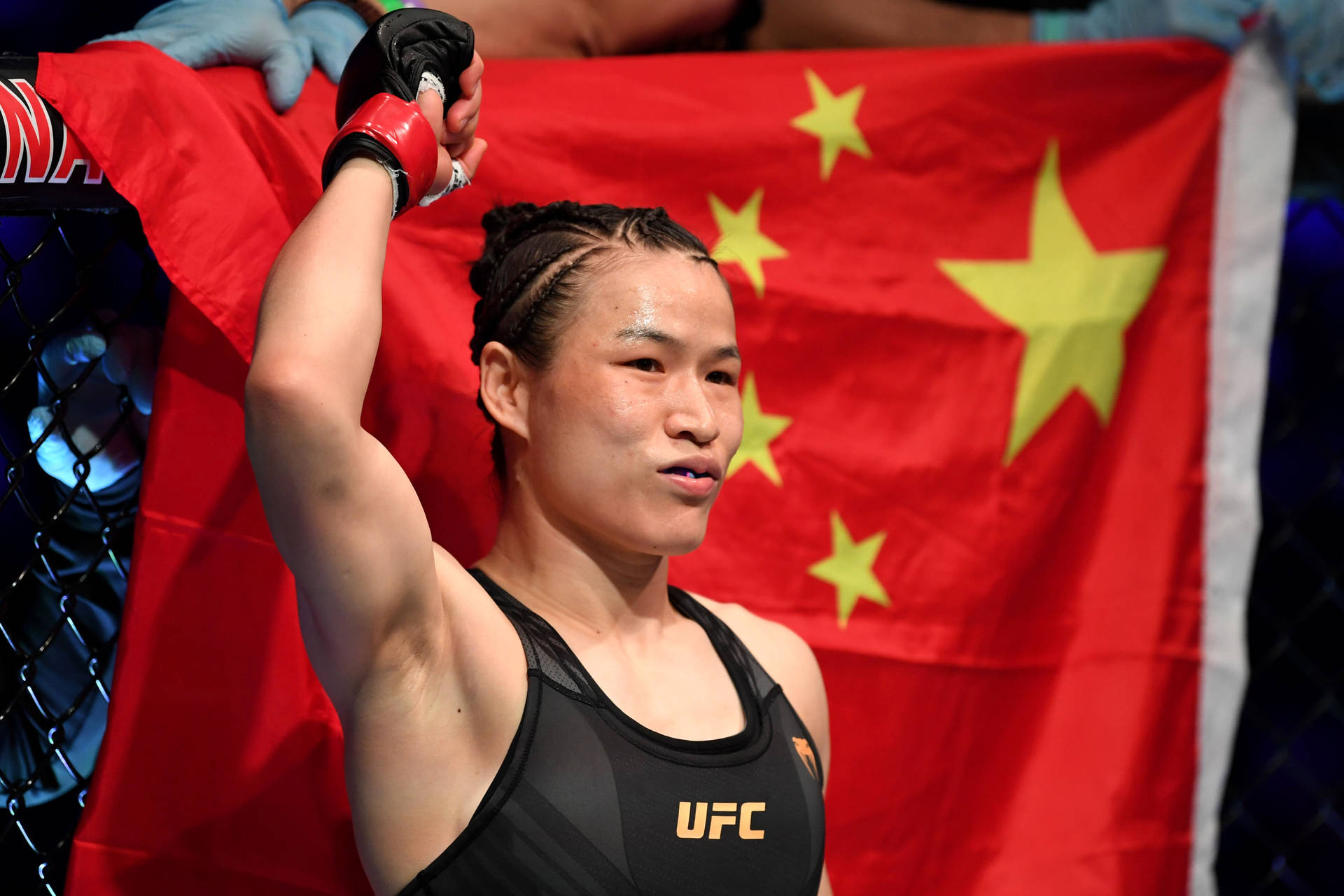 女性MMA拳手在UFC八角籠內手持中國國旗慶祝勝利。