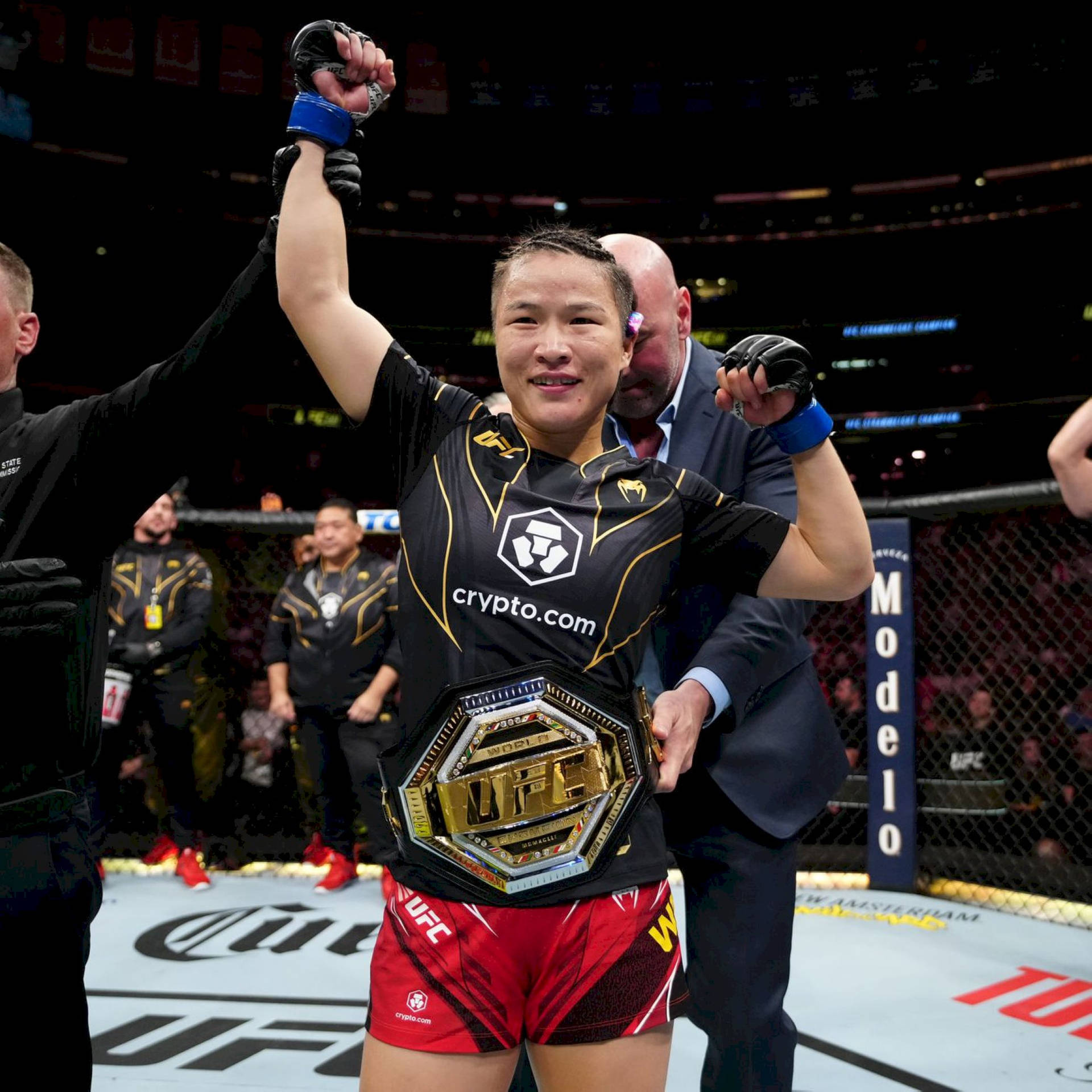 UFC拳手在八角籠中舉起冠軍腰帶慶祝勝利。