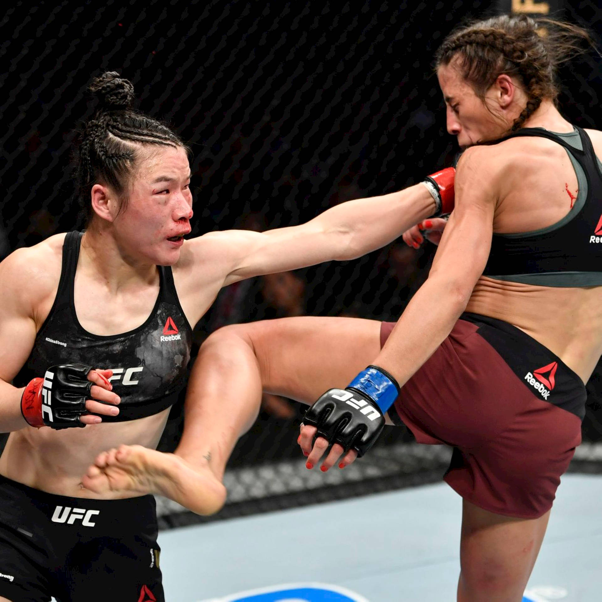 兩名女性MMA拳手在鐵籠賽中交換高踢和防守阻擋。