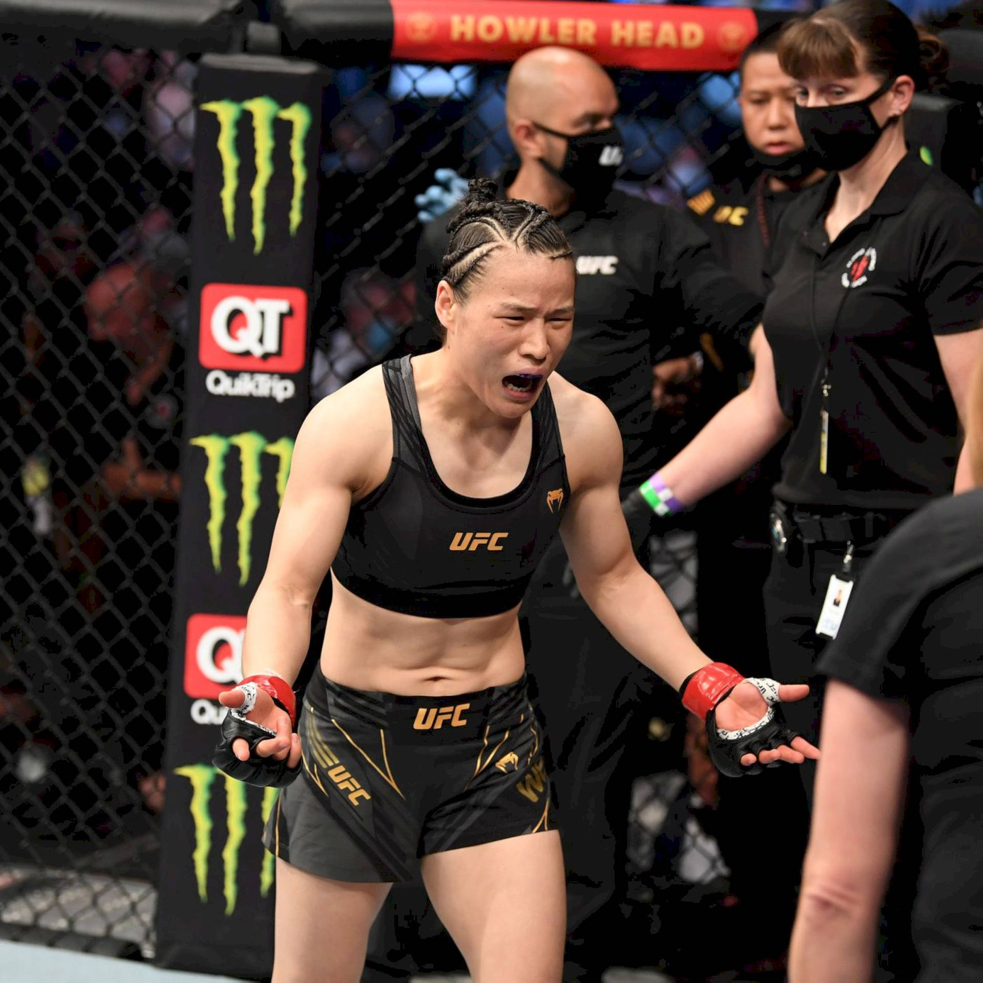 女MMA拳手在UFC八角籠中慶祝勝利，背景有官員。