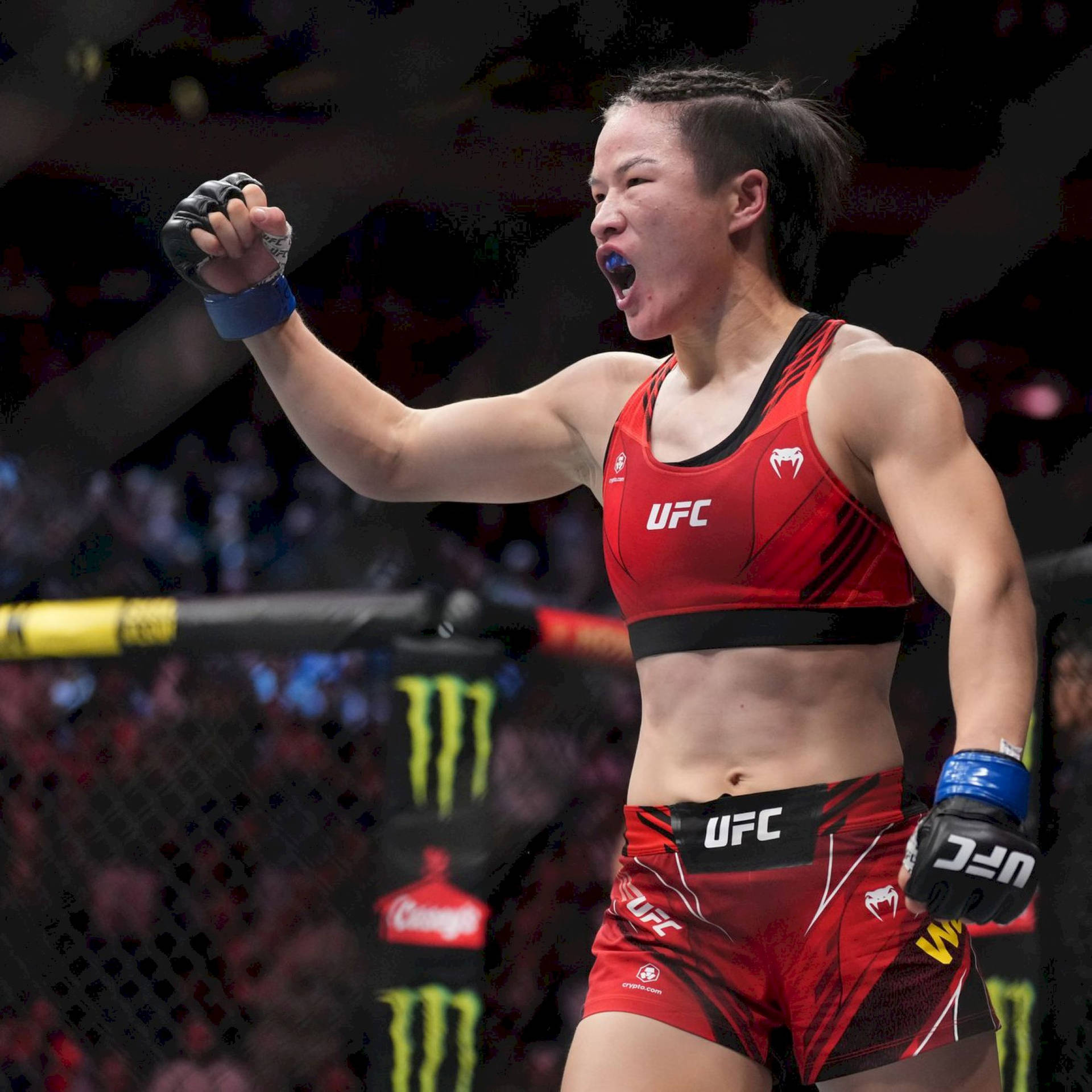 女性MMA拳手在UFC八角籠中高舉拳頭慶祝勝利。