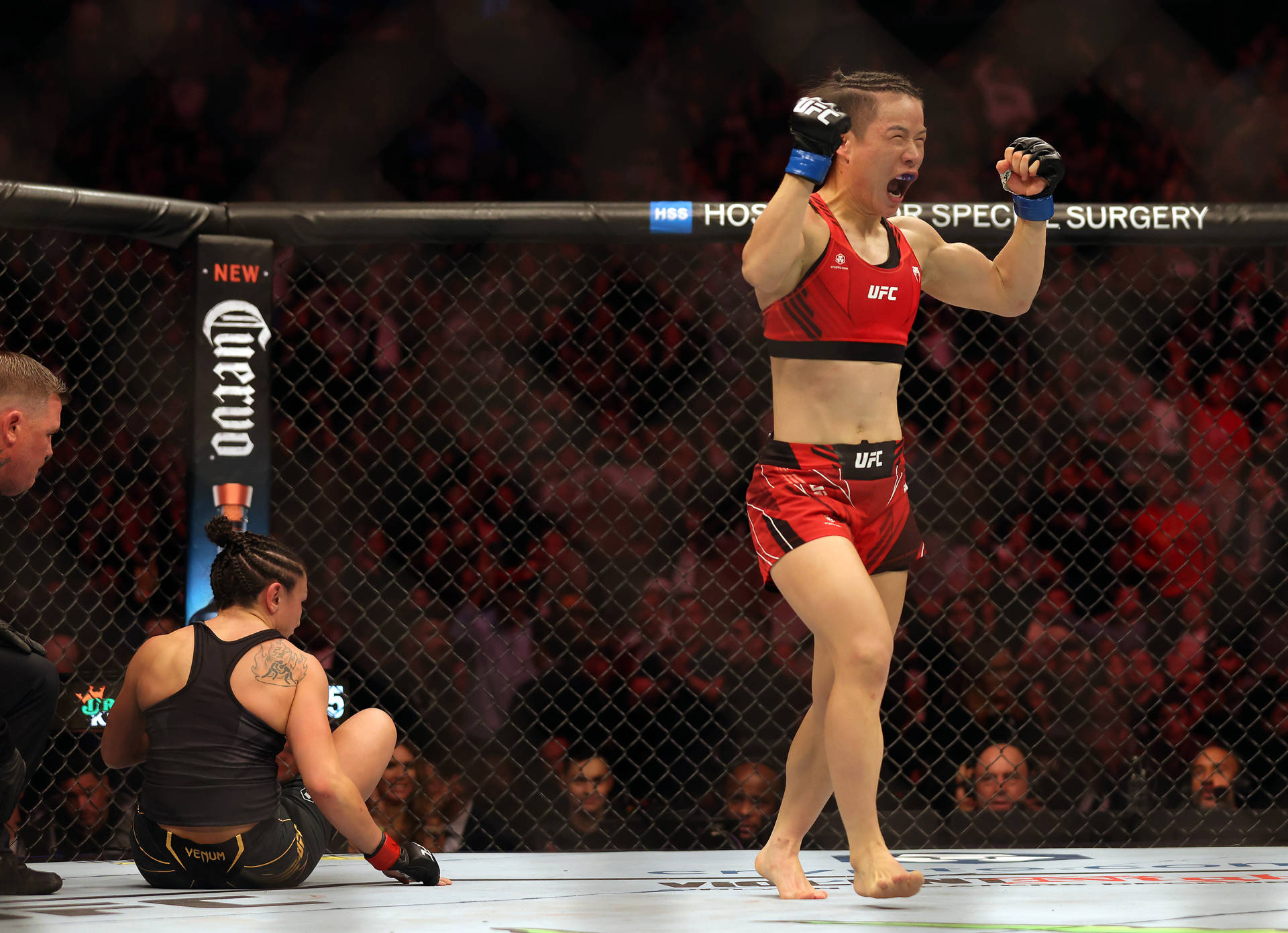 女性MMA拳手在擊敗對手後於八角籠中慶祝勝利。