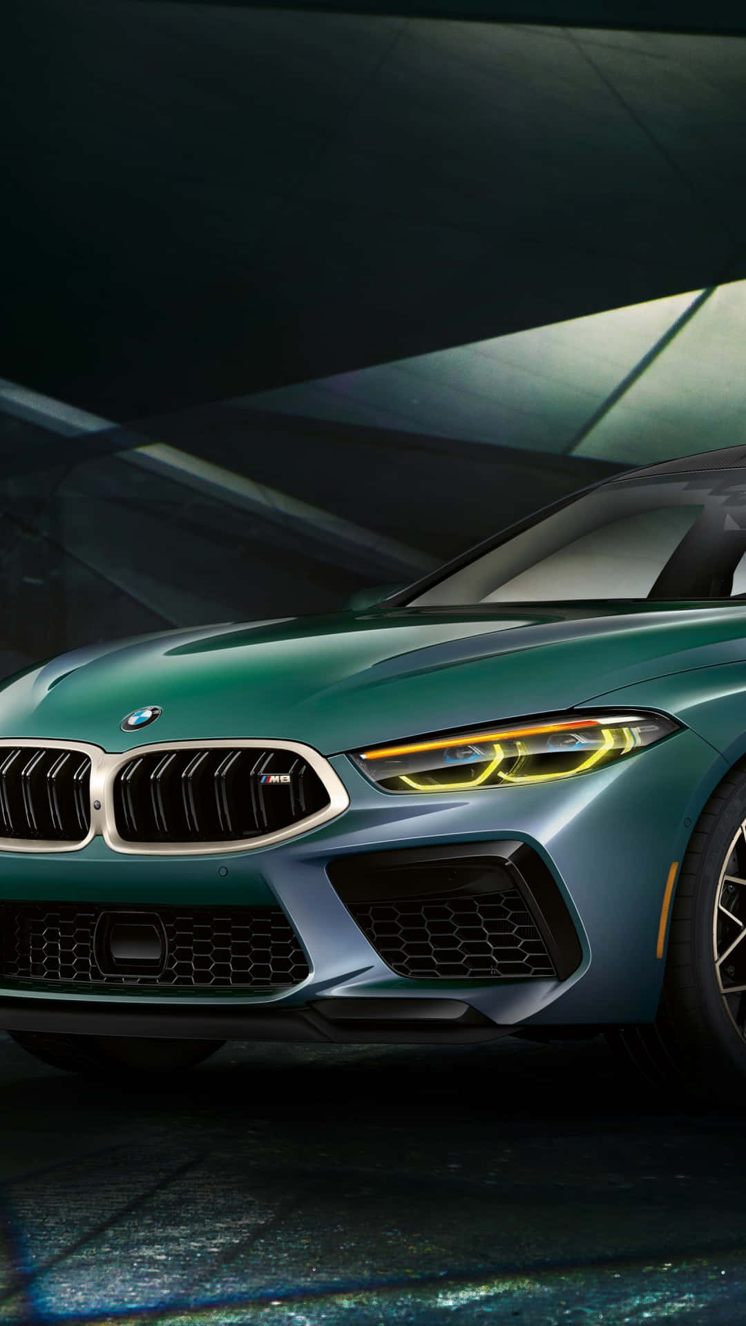 在黑暗的工作室環境中，一輛綠色BMW M8跑車配備發光的頭燈。