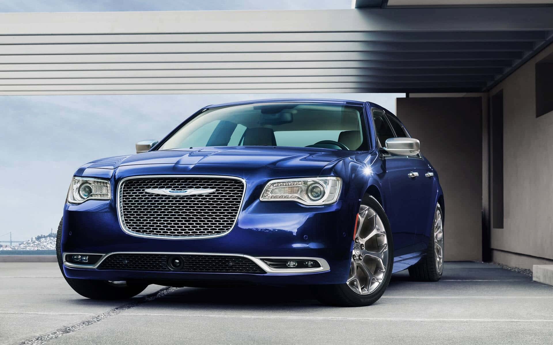 強勁有力的Chrysler 壁紙 — 一架時尚的藍色克萊斯勒轎車在日光下閃耀，停泊在現代混凝土簷篷下。