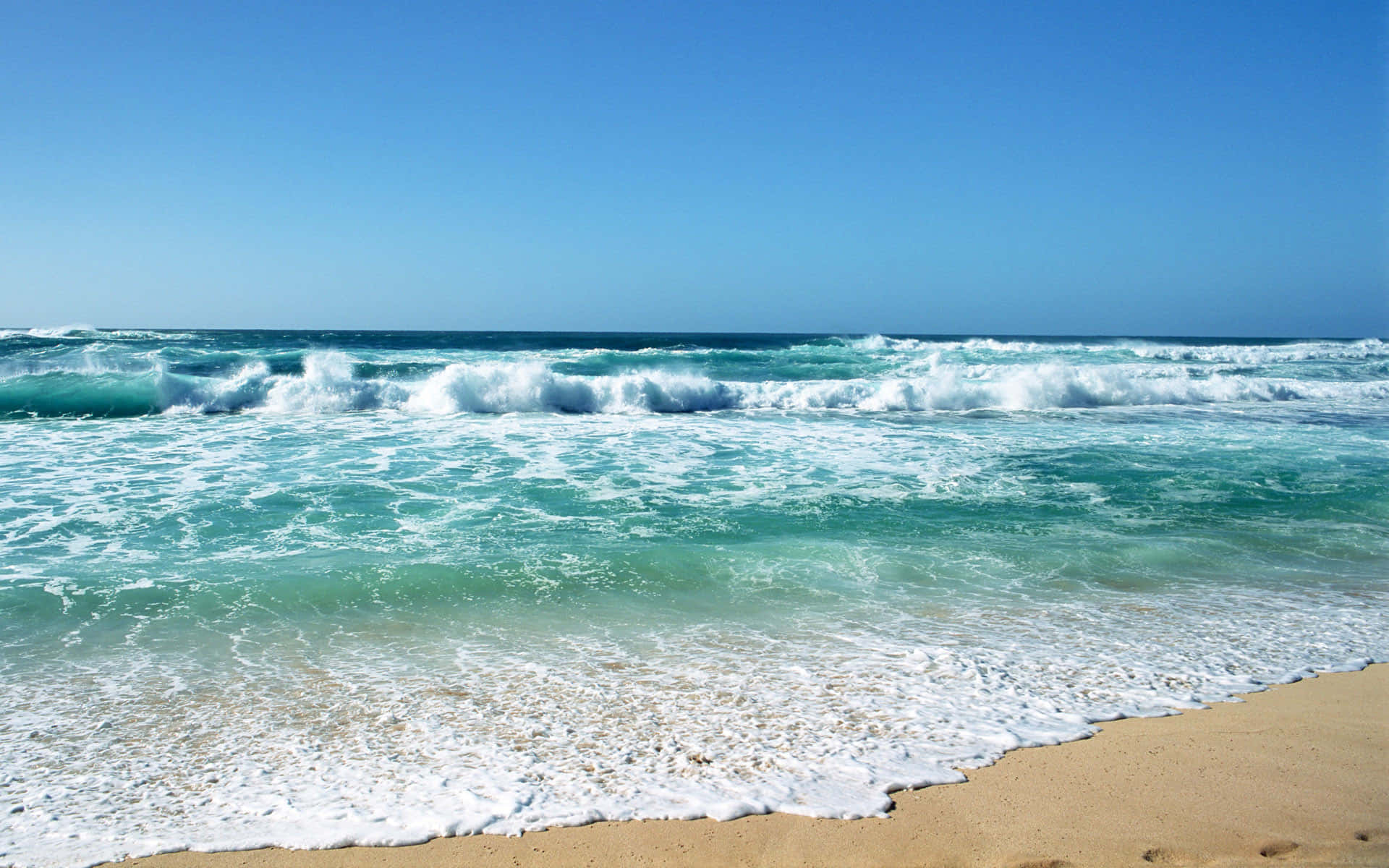 Beach Waves 桌布 壁紙 — 強勁的藍綠色海浪拍打著金色沙灘，天空湛藍清澈。