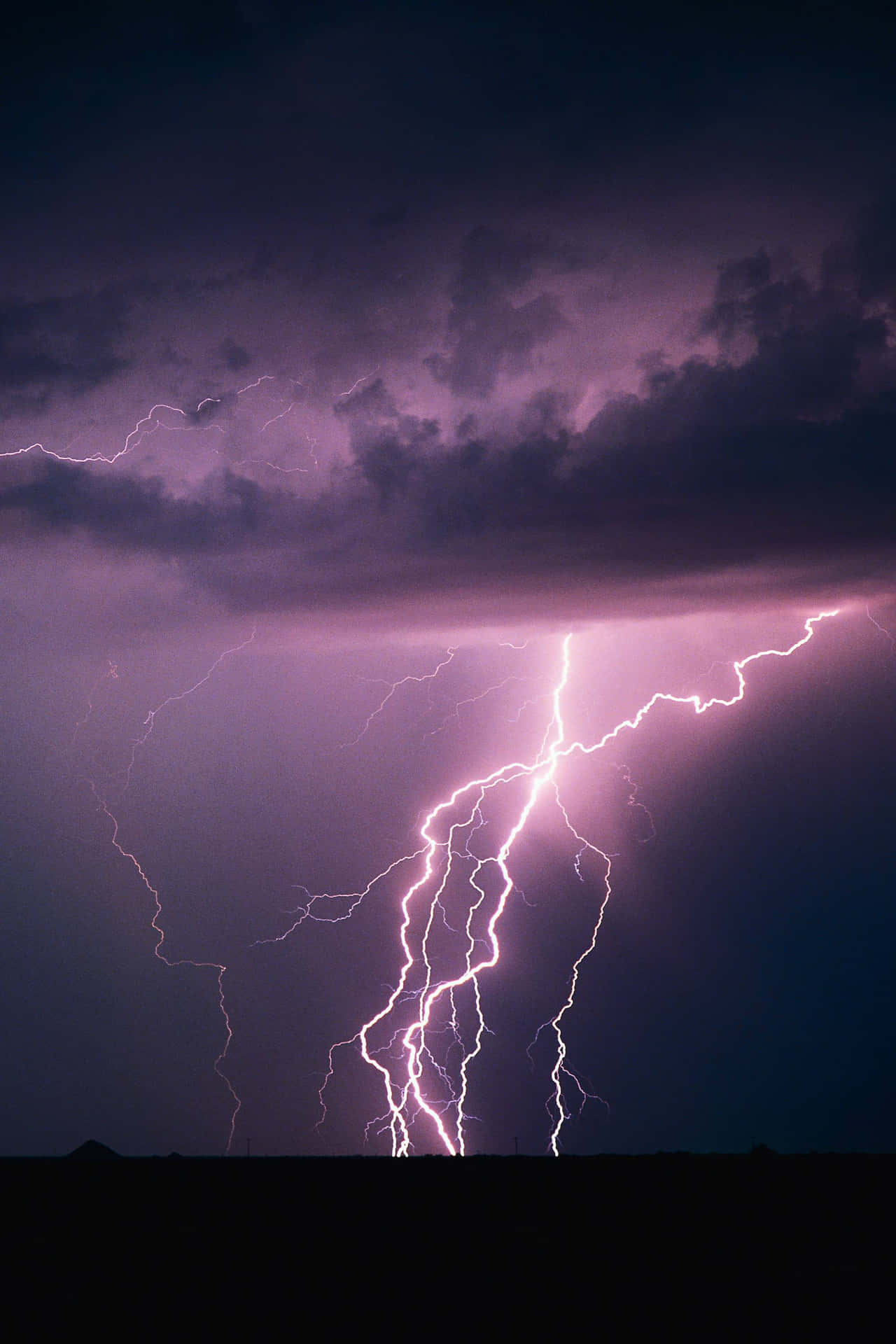 紫色閃電照亮了黑暗景觀上方的暴風雨夜空。