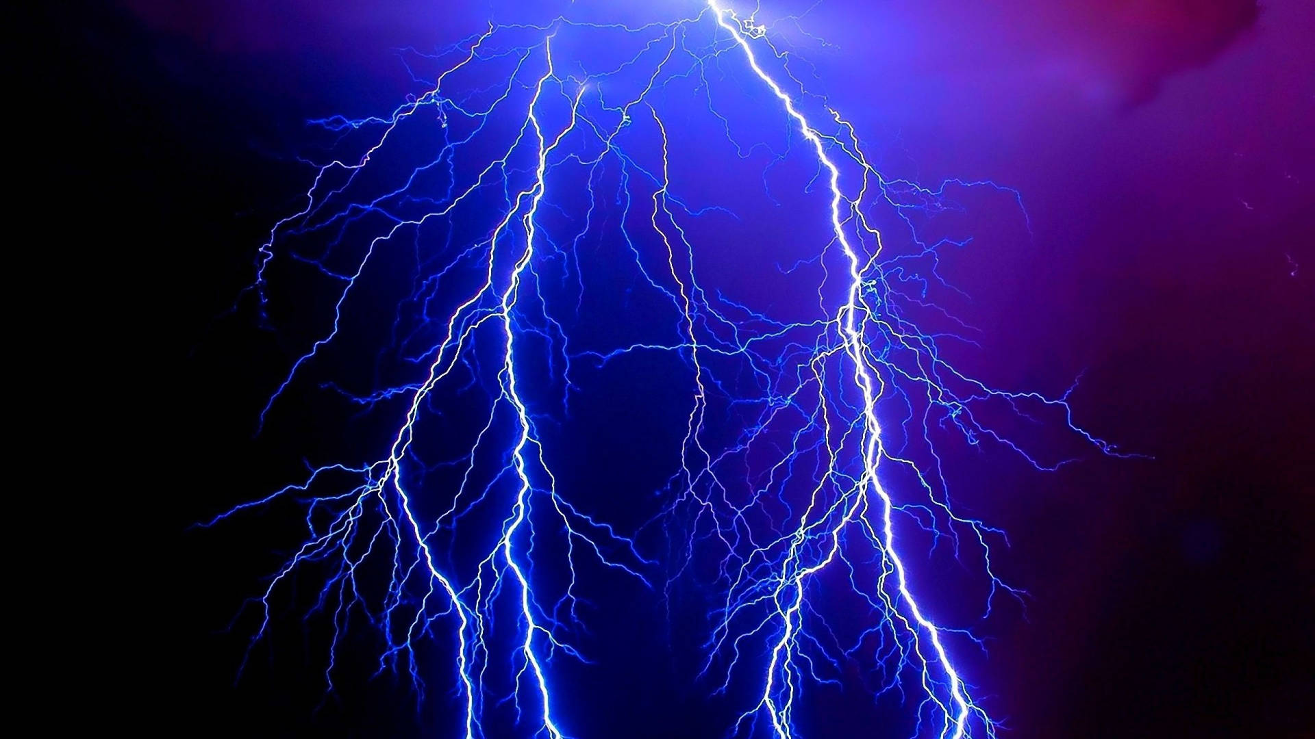 強烈的藍色閃電照亮了帶有紫色色調的黑暗暴風雨天空。