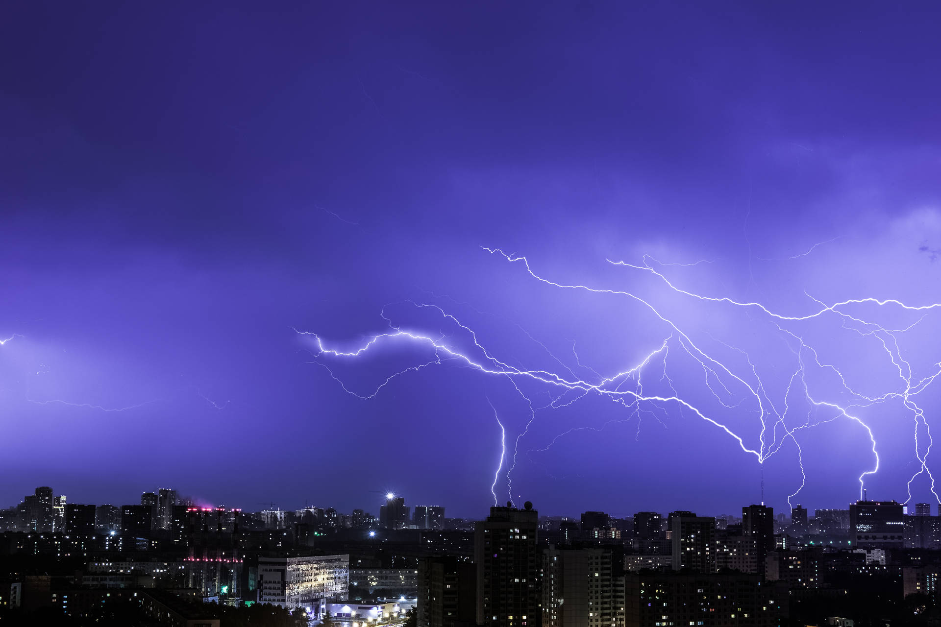 在紫色天空下，閃電擊中夜晚的城市。